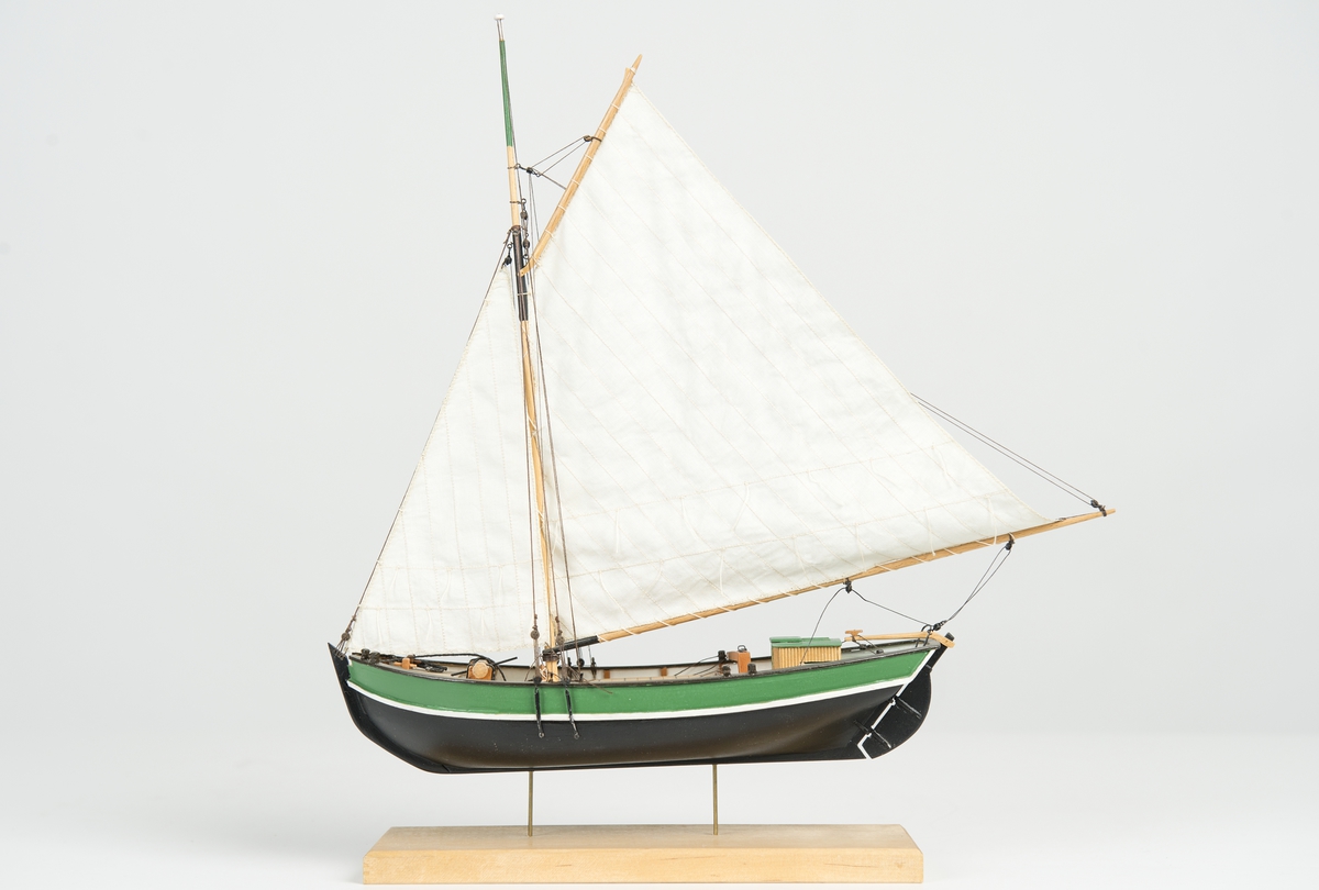 Riggad med fock och gaffelstorsegel. Svart skrov, grön bredgång. Vit kaltopp. Modellen tillverkad till utställningen "Seglande kungar, kungliga seglare", KSSS 150-årsjubileum 1980.