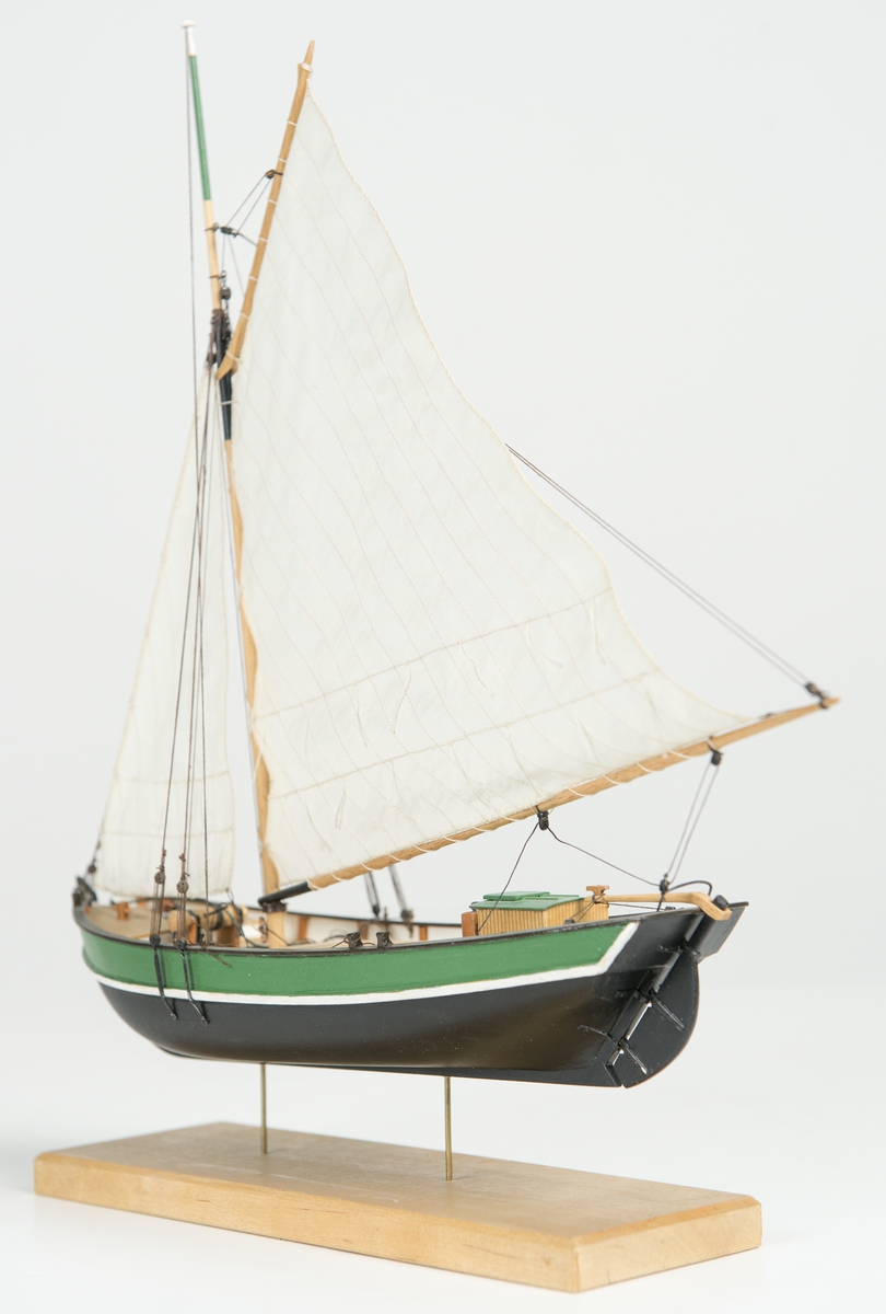 Riggad med fock och gaffelstorsegel. Svart skrov, grön bredgång. Vit kaltopp. Modellen tillverkad till utställningen "Seglande kungar, kungliga seglare", KSSS 150-årsjubileum 1980.