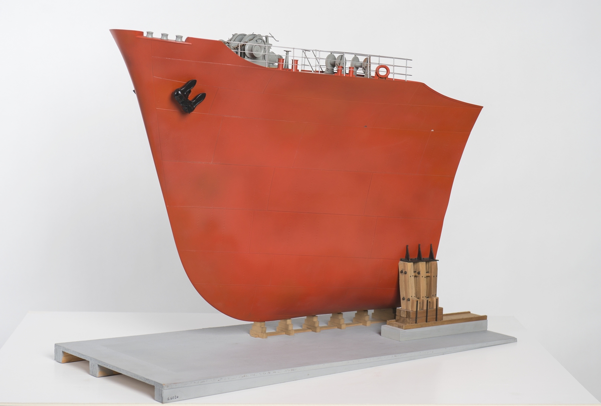 Modell av förskepp, från förstäv till mitten av l:ans lucka, byggd av metall, styrbords sida borttagen, visande konstruktionen med bottenstockar, spant, tanktak, skott och däck. Helt rödmålad. På backen gråmålat ankarspel och wirerullar. Under backen stor wirerulle. Två svarta ankare, stuvade i kättingbox.