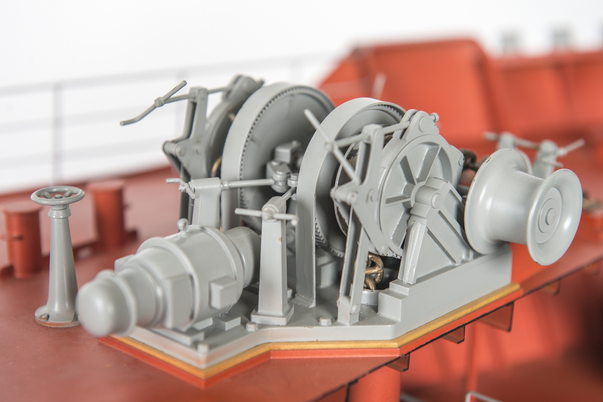 Modell av förskepp, från förstäv till mitten av l:ans lucka, byggd av metall, styrbords sida borttagen, visande konstruktionen med bottenstockar, spant, tanktak, skott och däck. Helt rödmålad. På backen gråmålat ankarspel och wirerullar. Under backen stor wirerulle. Två svarta ankare, stuvade i kättingbox.