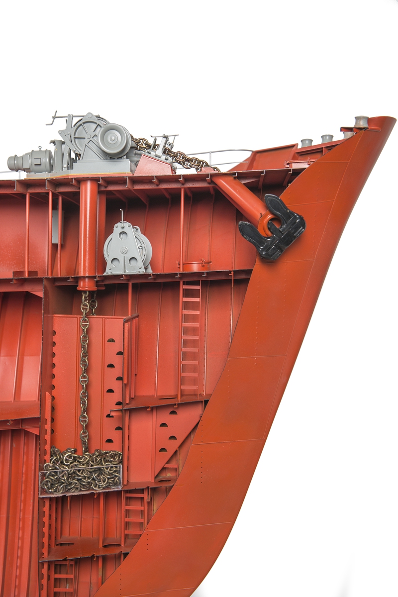 Modell av förskepp, från förstäv till mitten av l:ans lucka, byggd av metall, styrbords sida borttagen, visande konstruktionen med bottenstockar, spant, tanktak, skott och däck. Helt rödmålad. På backen gråmålat ankarspel och wirerullar. Under backen stor wirerulle. Två svarta ankare, stuvade i kättingbox.