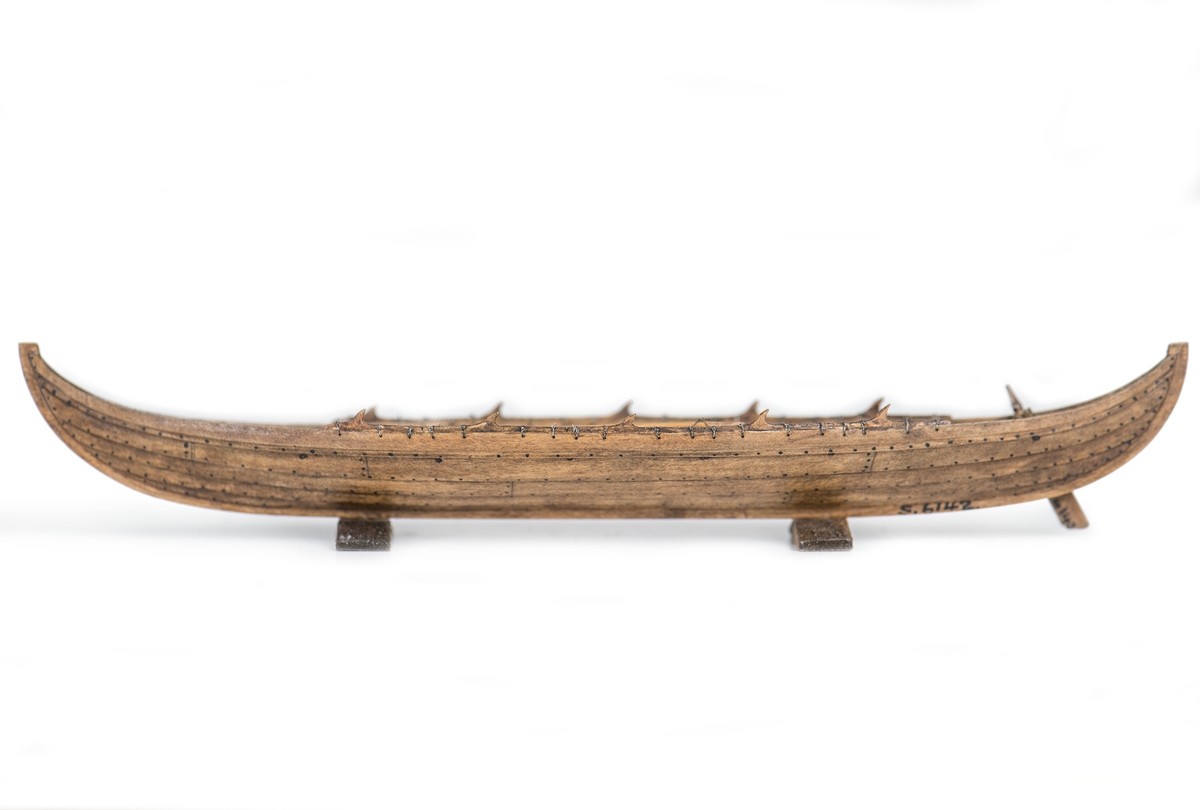 Rekonstruktion av gravbåt nr 2 från gravfältet vid Valsgärde i Uppland utgrävt 1928.
Skrov utfört i två halvor med limfog genom köl och stävar, bordläggningen skuren på såväl in- som utsidan. Klamparna på borden pålimmade. Håarna av grankvistar med självvuxen knagge, fastbundna med svartoxiderad suturtråd. Skrovet betsat i tjärfärg.
Inredning: 5 tofter, 4 åror samt styråra.