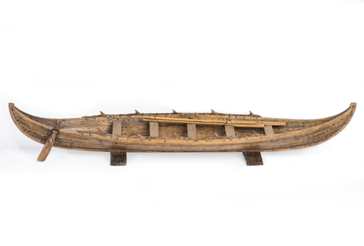 Rekonstruktion av gravbåt nr 2 från gravfältet vid Valsgärde i Uppland utgrävt 1928.
Skrov utfört i två halvor med limfog genom köl och stävar, bordläggningen skuren på såväl in- som utsidan. Klamparna på borden pålimmade. Håarna av grankvistar med självvuxen knagge, fastbundna med svartoxiderad suturtråd. Skrovet betsat i tjärfärg.
Inredning: 5 tofter, 4 åror samt styråra.