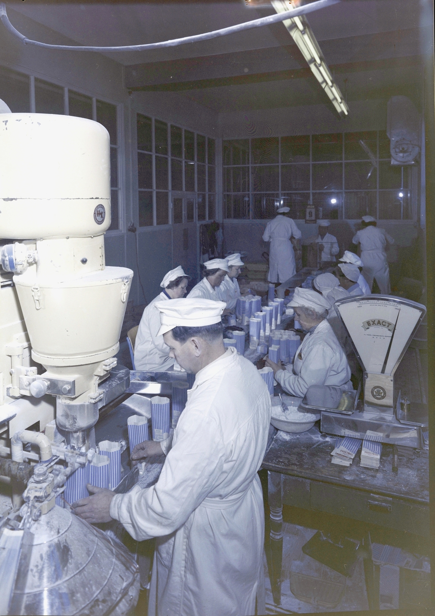 Brumunddal Potetmel- og Sagofabrikk, Brumunddal, Ringsaker. En gruppe arbeidere. Første fra venstre: Olava Bakkerud(?), Oline Midtbruket, ellers ukjente personer. Fabrikk, fabrikkarbeid, fabrikklokale, kvinnearbeidsplass. Pakking av potetmel i poser, samlebånd.