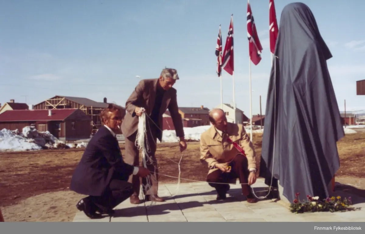 Bildet viser bysten over Kalle Rasmussen som har kommet på plass utenfor Miljøbygget i Vadsø. De siste forberedelsene om morgenen 17.mai 1978 før avdukingen av bysten er i gang.Fra venstre: Taba Pedersen, Gunnar Niska og Torbjørn Nordgård. Foto: Per Bjørgan.