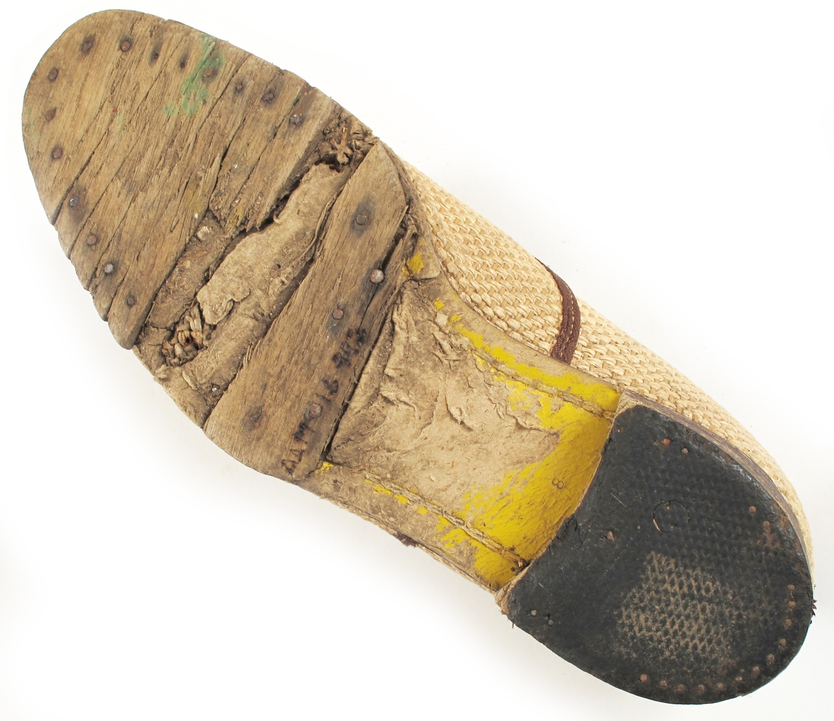 Damesko, krisevare fra tiden 1943 - 45.  
Såle tre, leddet. Hælen har gummi ytterst. Mellom sålen og overdelen er der pressa  papp, gulmalt. Overdelen beige,  vevd stoff der renning og innslag  et tvinna papirprodukt. Tå og hælkappe  samt åpninga foran av fiskeskinn.  mellombrunt. Brune bånd. tekstil, sydd rundt åpninga og dessuten som buet pynt  tversover. Snøring og 5 maljer