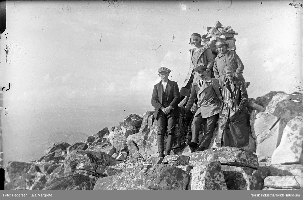 Mennesker stående ved varde på fjell.