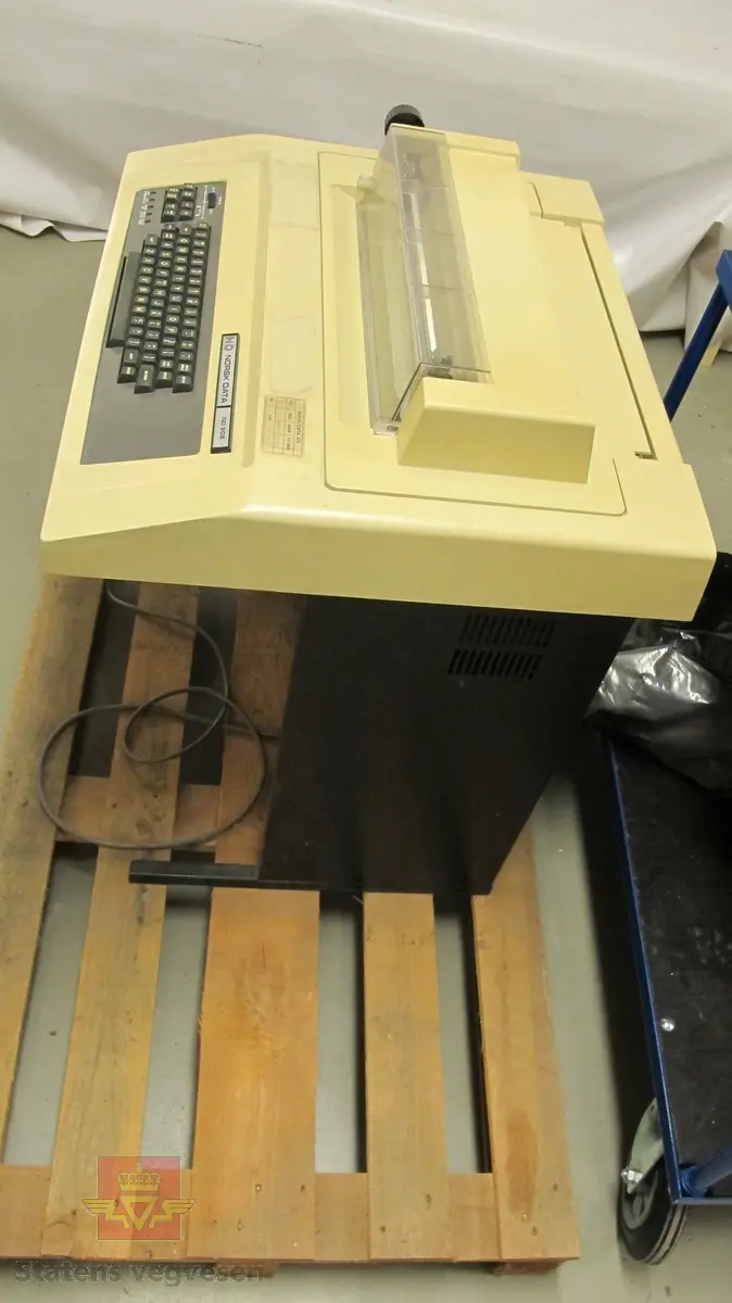 Beige terminal på svart ramme. Terminalen er intakt men bærer preg av å ha stått en stund. Det er også flere klistremerker som har falt av eller har blitt fjernet. Tastaturet er grått med et lite instrumentpanel på venstre side der man kan stille inn print.

På undersiden av rammen sitter det sikringer og maskinens strømledning.

Toppen av terminalen kan åpnes for å skifte printerkassett og lignende. Ellers er terminalen i god stand.