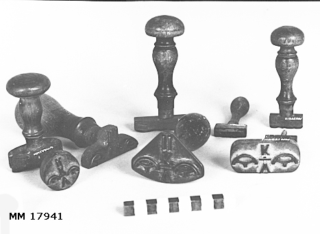 Stämplar av mässing, vissa gängade till träskaft. Olika format, samtliga försedda med kronostämpel, typ kattfot på vardera sida om bokstäverna. Spår av röd färg.
MM 17941.2 : V K