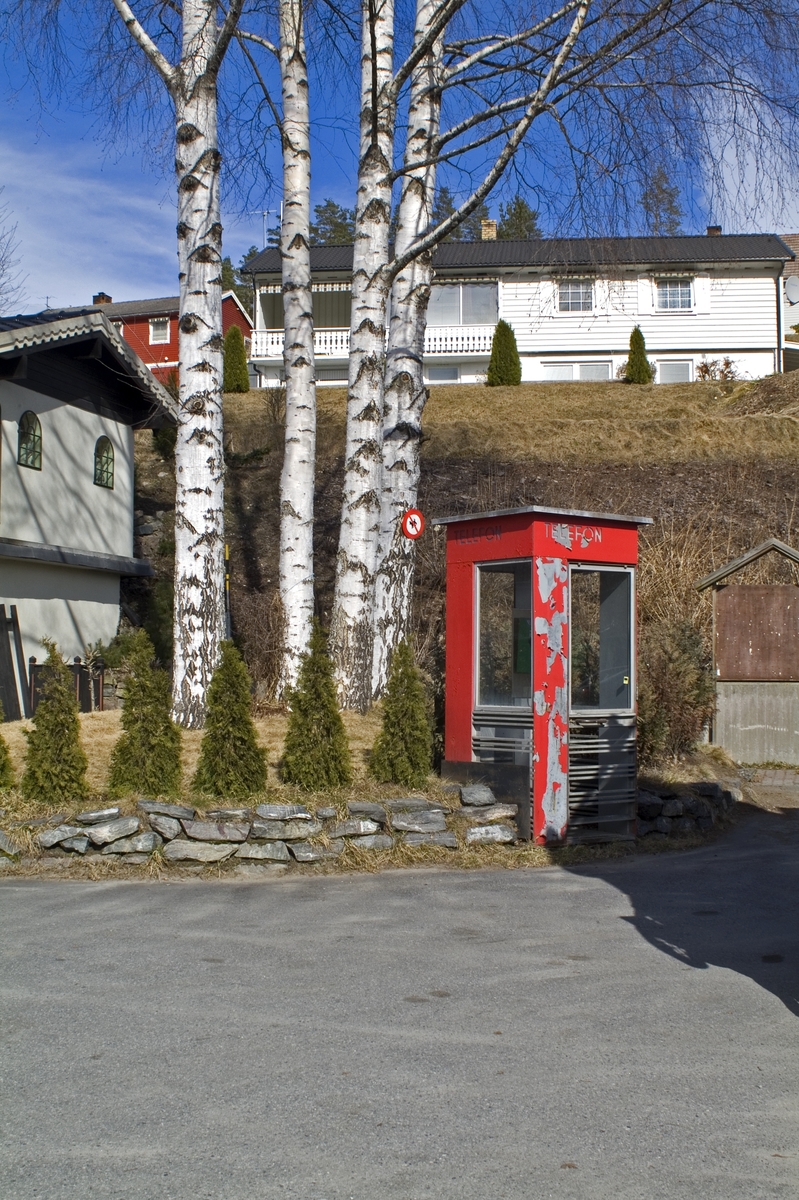 This is the story of how Norway’s most important conversation-space was designed by a young, freshly graduated man from Bergen.

“Norwegian architects are hereby invited…”
In the autumn of 1932, Oslo Telefonanlegginitiated an architectural competition. Finally, Oslo would get its own telephone booth. The city had had so called “talking-stations” from 1885, which in turn were overtaken by automatic telephones 
 only available at selected Narvesen kiosks. The state 
was of the opinion that now was the time to offer the public a better service; public telephone booths open 24/7, like the ones they already had in Sweden and England. But what would they look like, these new telephone booths? What considerations would it
 be necessary to take when designing it? The telegraph board developed a detailed list of demands and restraints: “The booth is intended to be placed outside on the streets and squares and need to be designed so that snow and ice does not hinder the opening and closing of the doors,” they wrote. “To prevent vandalism, theft, uncleanliness etc. inside the booth, it needs to be designed so that from all angles one may see what is going on in there.” Additionally, it would need to withstand storms and bad weather, and “preferably also being whipped by rain mixed with seawater” 

This was not all: The appearance would have to be «pleasing». The booth also needed to be movable, so that it could be taken in to be serviced at Telegrafverket’s main workshops. The reqired material was iron, and the surface was to be spray painted  preferably using car-body paint. There was a requirement for “a writing shelf, a pack shelf, and a suitable place for the telephone catalogue.” Also, there would need to be an illuminated TELEFON  sign, easily visible from all four angles. The total cost for each booth should not exceed 1000 kroner. The first prize for coming up with such a product was 800 kroner.

“Norwegianarchitects are hereby invited to partake in a competition for the design of a telephone booth…”  

The man with the solution
«At some point in 1932, Georg Fredrik sat at a party in Bergen. Maybe he felt a bit lost and forgotten as he often had throughout his life. He retreated to a quiet corner, took out a pencil and strted doodling on a matchbox.  According to my mother, this was how the telephone booth came into being.” In the book “Norges lille røde  historien om telefonkiosken,” Lars Fasting describes his father, the man who is far less known than the iconic architctural structure he left behind. Georg Fredrik Fasting was from Bergen, born into a family of working people and smallholders. One unusual facet of Georg Fredrik was that he was born without ears. His mother made sure he learnt to speak, read and write, 
ut Lars Fasting indicates that his father would seek refuge in drawing when the social challenges became too much to bear. And in the end drawing became his profession. In 1924 he secured a guarantor for a student loan, and started studying to become an a
rchitect at the NTH. Throughout the 1930s he entered several architectural competitions, with drafts produced, according to his son, “after work and in the late hours of the night.”

His efforts were not wasted. Out of 93 entries, with names such as “Flirt”, “Brrr”, “Ring” and “Amor”, the jury selected Fasting’s submission, “RIKS” as the new telephone booth: “The draft shows a strikingly simple solution to the task, technically as well as aesthetically well worked out.”

Taut and provident
Simple and aesthetc are the keywords here. Fasting had designed a booth pointing towards the future, and to modernism. Just how modern it was can be seen by comparing RIKS to the British telephone booth, also designed in the interwar-era. While the British version with it classicistic style is looking back to the heyday of the empire, Fasting’s booth is progressive and functionalistic. Like most Norwegian architects, Fasting broke with the classicistic style of architecture after the Stockholm-exhibition in 1930. “After it, almost all buildings erected in Norway until the German invasion in 1940, were in the functionalistic architectural style,” writes senior curator of architecture at the Norwegian National Museum, Ulf Grønvold, in the book, “Den lille røde”.“TheNorwegian booth is a piece of functionalistic architecture, an asymmetric composition with its roof slab overhanging the word TELEFON, in bold sans seraph lettering,”concludes Ulf Grønvold.

Fashionably red
And it was red. Fasting chose a colour which was part of the modern palette. “A bright red colour, but not as shiny as a signal red, the character of the colour places it among the fashionable colours within functionalism,” states paintings conservator and researcher in NIKU (Norwegian Institute for Cultural Heitage Research), Jon Brænne. In his opinion, Fasting went for visibility without making the booth stand out too much from its surroundings. The original colour was in use up to around 1950, when it changed to signal red. Towards the end of the 1970s the clour was again adjusted towards today’s orangey red.

The design, however, has not changed. RIKS is eighty years and still looks remarkably good. That’s what makes Fasting’s telephone booth a classic  even before it was added to DOCOMOMO’s list over moden icons of design. For Telenor, the telephone booth has served as a pathway into the hearts of the public. For many, Telenor (Televerket) was synonymous with exactly this telephone booth, because this was where one would go to place a call. Having a home
phone was not common until the 1980s. As such the red box became part of the Norwegian everyday and consciousness. The symbol- and publicity value of this is hard to evaluate, but in 2007 it was time to give honour where honour was due, Telenor, in consul
tation with the Directorate for Cultural Heritage, decided to preserve 100 telephone booths for all eternity.

And what about Georg Fredrik Fasting? What happened to him? At the age of 56 an entry in his diary states: «I CAN HEAR». As the first person in th world he had undergone an operation where he had ear canals constructed and eardrums fitted. For the rest of his life, the man behind Norway’s own telephone booth could answer the telephone himself.

Source: Norges lille røde historien om telefonkiosken (2007), issued by The Norwegian Telecom Museum and Telenor Cultural Heritage.