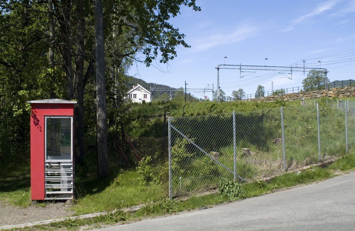 This is the story of how Norway’s most important conversation-space was designed by a young, freshly graduated man from Bergen.

“Norwegian architects are hereby invited…”
In the autumn of 1932, Oslo Telefonanlegginitiated an architectural competition. Finally, Oslo would get its own telephone booth. The city had had so called “talking-stations” from 1885, which in turn were overtaken by automatic telephones 
 only available at selected Narvesen kiosks. The state 
was of the opinion that now was the time to offer the public a better service; public telephone booths open 24/7, like the ones they already had in Sweden and England. But what would they look like, these new telephone booths? What considerations would it
 be necessary to take when designing it? The telegraph board developed a detailed list of demands and restraints: “The booth is intended to be placed outside on the streets and squares and need to be designed so that snow and ice does not hinder the opening and closing of the doors,” they wrote. “To prevent vandalism, theft, uncleanliness etc. inside the booth, it needs to be designed so that from all angles one may see what is going on in there.” Additionally, it would need to withstand storms and bad weather, and “preferably also being whipped by rain mixed with seawater” 

This was not all: The appearance would have to be «pleasing». The booth also needed to be movable, so that it could be taken in to be serviced at Telegrafverket’s main workshops. The reqired material was iron, and the surface was to be spray painted  preferably using car-body paint. There was a requirement for “a writing shelf, a pack shelf, and a suitable place for the telephone catalogue.” Also, there would need to be an illuminated TELEFON  sign, easily visible from all four angles. The total cost for each booth should not exceed 1000 kroner. The first prize for coming up with such a product was 800 kroner.

“Norwegianarchitects are hereby invited to partake in a competition for the design of a telephone booth…”  

The man with the solution
«At some point in 1932, Georg Fredrik sat at a party in Bergen. Maybe he felt a bit lost and forgotten as he often had throughout his life. He retreated to a quiet corner, took out a pencil and strted doodling on a matchbox.  According to my mother, this was how the telephone booth came into being.” In the book “Norges lille røde  historien om telefonkiosken,” Lars Fasting describes his father, the man who is far less known than the iconic architctural structure he left behind. Georg Fredrik Fasting was from Bergen, born into a family of working people and smallholders. One unusual facet of Georg Fredrik was that he was born without ears. His mother made sure he learnt to speak, read and write, 
ut Lars Fasting indicates that his father would seek refuge in drawing when the social challenges became too much to bear. And in the end drawing became his profession. In 1924 he secured a guarantor for a student loan, and started studying to become an a
rchitect at the NTH. Throughout the 1930s he entered several architectural competitions, with drafts produced, according to his son, “after work and in the late hours of the night.”

His efforts were not wasted. Out of 93 entries, with names such as “Flirt”, “Brrr”, “Ring” and “Amor”, the jury selected Fasting’s submission, “RIKS” as the new telephone booth: “The draft shows a strikingly simple solution to the task, technically as well as aesthetically well worked out.”

Taut and provident
Simple and aesthetc are the keywords here. Fasting had designed a booth pointing towards the future, and to modernism. Just how modern it was can be seen by comparing RIKS to the British telephone booth, also designed in the interwar-era. While the British version with it classicistic style is looking back to the heyday of the empire, Fasting’s booth is progressive and functionalistic. Like most Norwegian architects, Fasting broke with the classicistic style of architecture after the Stockholm-exhibition in 1930. “After it, almost all buildings erected in Norway until the German invasion in 1940, were in the functionalistic architectural style,” writes senior curator of architecture at the Norwegian National Museum, Ulf Grønvold, in the book, “Den lille røde”.“TheNorwegian booth is a piece of functionalistic architecture, an asymmetric composition with its roof slab overhanging the word TELEFON, in bold sans seraph lettering,”concludes Ulf Grønvold.

Fashionably red
And it was red. Fasting chose a colour which was part of the modern palette. “A bright red colour, but not as shiny as a signal red, the character of the colour places it among the fashionable colours within functionalism,” states paintings conservator and researcher in NIKU (Norwegian Institute for Cultural Heitage Research), Jon Brænne. In his opinion, Fasting went for visibility without making the booth stand out too much from its surroundings. The original colour was in use up to around 1950, when it changed to signal red. Towards the end of the 1970s the clour was again adjusted towards today’s orangey red.

The design, however, has not changed. RIKS is eighty years and still looks remarkably good. That’s what makes Fasting’s telephone booth a classic  even before it was added to DOCOMOMO’s list over moden icons of design. For Telenor, the telephone booth has served as a pathway into the hearts of the public. For many, Telenor (Televerket) was synonymous with exactly this telephone booth, because this was where one would go to place a call. Having a home
phone was not common until the 1980s. As such the red box became part of the Norwegian everyday and consciousness. The symbol- and publicity value of this is hard to evaluate, but in 2007 it was time to give honour where honour was due, Telenor, in consul
tation with the Directorate for Cultural Heritage, decided to preserve 100 telephone booths for all eternity.

And what about Georg Fredrik Fasting? What happened to him? At the age of 56 an entry in his diary states: «I CAN HEAR». As the first person in th world he had undergone an operation where he had ear canals constructed and eardrums fitted. For the rest of his life, the man behind Norway’s own telephone booth could answer the telephone himself.

Source: Norges lille røde historien om telefonkiosken (2007), issued by The Norwegian Telecom Museum and Telenor Cultural Heritage.