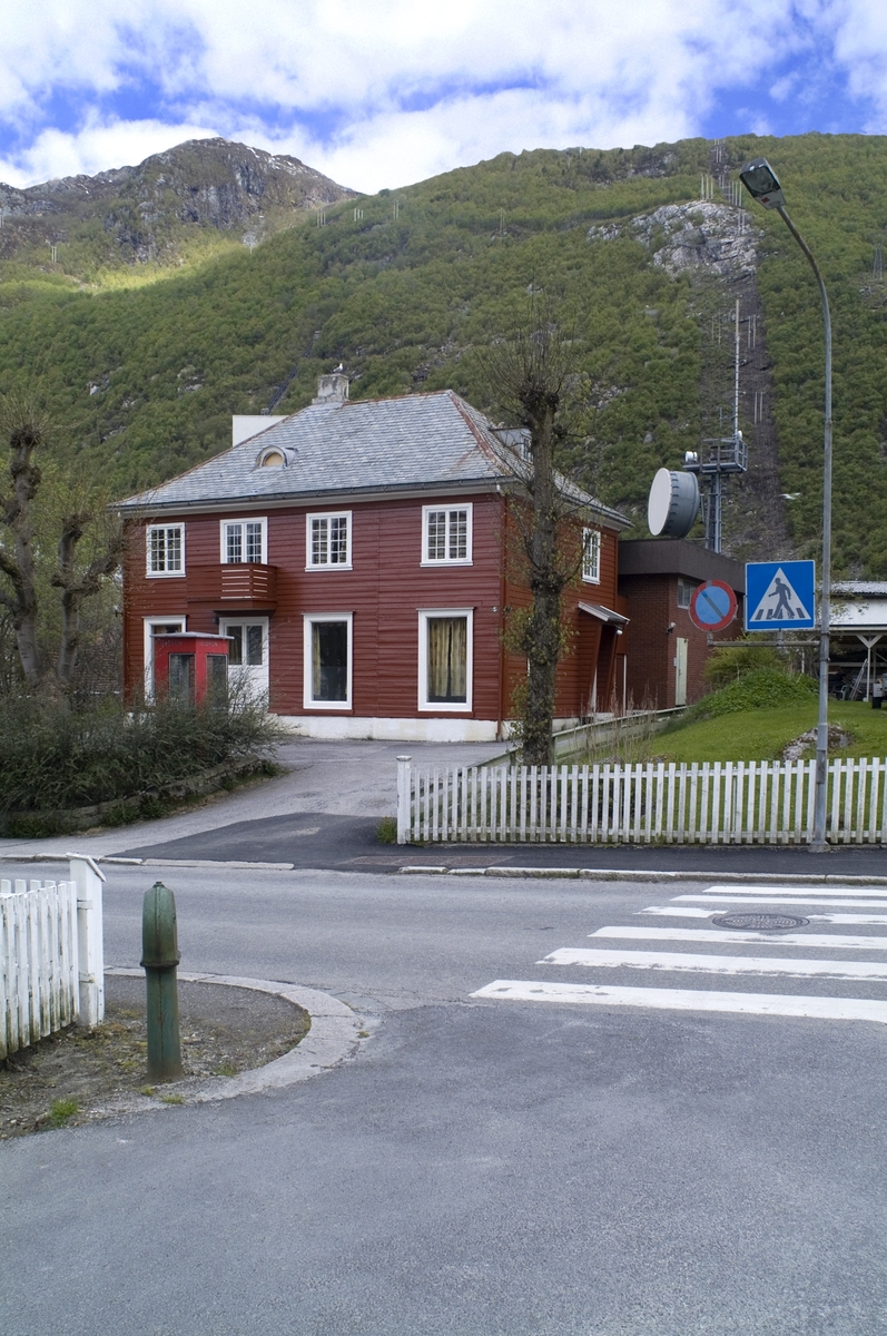 This is the story of how Norway’s most important conversation-space was designed by a young, freshly graduated man from Bergen.

“Norwegian architects are hereby invited…”
In the autumn of 1932, Oslo Telefonanlegginitiated an architectural competition. Finally, Oslo would get its own telephone booth. The city had had so called “talking-stations” from 1885, which in turn were overtaken by automatic telephones 
 only available at selected Narvesen kiosks. The state 
was of the opinion that now was the time to offer the public a better service; public telephone booths open 24/7, like the ones they already had in Sweden and England. But what would they look like, these new telephone booths? What considerations would it
 be necessary to take when designing it? The telegraph board developed a detailed list of demands and restraints: “The booth is intended to be placed outside on the streets and squares and need to be designed so that snow and ice does not hinder the opening and closing of the doors,” they wrote. “To prevent vandalism, theft, uncleanliness etc. inside the booth, it needs to be designed so that from all angles one may see what is going on in there.” Additionally, it would need to withstand storms and bad weather, and “preferably also being whipped by rain mixed with seawater” 

This was not all: The appearance would have to be «pleasing». The booth also needed to be movable, so that it could be taken in to be serviced at Telegrafverket’s main workshops. The reqired material was iron, and the surface was to be spray painted  preferably using car-body paint. There was a requirement for “a writing shelf, a pack shelf, and a suitable place for the telephone catalogue.” Also, there would need to be an illuminated TELEFON  sign, easily visible from all four angles. The total cost for each booth should not exceed 1000 kroner. The first prize for coming up with such a product was 800 kroner.

“Norwegianarchitects are hereby invited to partake in a competition for the design of a telephone booth…”  

The man with the solution
«At some point in 1932, Georg Fredrik sat at a party in Bergen. Maybe he felt a bit lost and forgotten as he often had throughout his life. He retreated to a quiet corner, took out a pencil and strted doodling on a matchbox.  According to my mother, this was how the telephone booth came into being.” In the book “Norges lille røde  historien om telefonkiosken,” Lars Fasting describes his father, the man who is far less known than the iconic architctural structure he left behind. Georg Fredrik Fasting was from Bergen, born into a family of working people and smallholders. One unusual facet of Georg Fredrik was that he was born without ears. His mother made sure he learnt to speak, read and write, 
ut Lars Fasting indicates that his father would seek refuge in drawing when the social challenges became too much to bear. And in the end drawing became his profession. In 1924 he secured a guarantor for a student loan, and started studying to become an a
rchitect at the NTH. Throughout the 1930s he entered several architectural competitions, with drafts produced, according to his son, “after work and in the late hours of the night.”

His efforts were not wasted. Out of 93 entries, with names such as “Flirt”, “Brrr”, “Ring” and “Amor”, the jury selected Fasting’s submission, “RIKS” as the new telephone booth: “The draft shows a strikingly simple solution to the task, technically as well as aesthetically well worked out.”

Taut and provident
Simple and aesthetc are the keywords here. Fasting had designed a booth pointing towards the future, and to modernism. Just how modern it was can be seen by comparing RIKS to the British telephone booth, also designed in the interwar-era. While the British version with it classicistic style is looking back to the heyday of the empire, Fasting’s booth is progressive and functionalistic. Like most Norwegian architects, Fasting broke with the classicistic style of architecture after the Stockholm-exhibition in 1930. “After it, almost all buildings erected in Norway until the German invasion in 1940, were in the functionalistic architectural style,” writes senior curator of architecture at the Norwegian National Museum, Ulf Grønvold, in the book, “Den lille røde”.“TheNorwegian booth is a piece of functionalistic architecture, an asymmetric composition with its roof slab overhanging the word TELEFON, in bold sans seraph lettering,”concludes Ulf Grønvold.

Fashionably red
And it was red. Fasting chose a colour which was part of the modern palette. “A bright red colour, but not as shiny as a signal red, the character of the colour places it among the fashionable colours within functionalism,” states paintings conservator and researcher in NIKU (Norwegian Institute for Cultural Heitage Research), Jon Brænne. In his opinion, Fasting went for visibility without making the booth stand out too much from its surroundings. The original colour was in use up to around 1950, when it changed to signal red. Towards the end of the 1970s the clour was again adjusted towards today’s orangey red.

The design, however, has not changed. RIKS is eighty years and still looks remarkably good. That’s what makes Fasting’s telephone booth a classic  even before it was added to DOCOMOMO’s list over moden icons of design. For Telenor, the telephone booth has served as a pathway into the hearts of the public. For many, Telenor (Televerket) was synonymous with exactly this telephone booth, because this was where one would go to place a call. Having a home
phone was not common until the 1980s. As such the red box became part of the Norwegian everyday and consciousness. The symbol- and publicity value of this is hard to evaluate, but in 2007 it was time to give honour where honour was due, Telenor, in consul
tation with the Directorate for Cultural Heritage, decided to preserve 100 telephone booths for all eternity.

And what about Georg Fredrik Fasting? What happened to him? At the age of 56 an entry in his diary states: «I CAN HEAR». As the first person in th world he had undergone an operation where he had ear canals constructed and eardrums fitted. For the rest of his life, the man behind Norway’s own telephone booth could answer the telephone himself.

Source: Norges lille røde historien om telefonkiosken (2007), issued by The Norwegian Telecom Museum and Telenor Cultural Heritage.