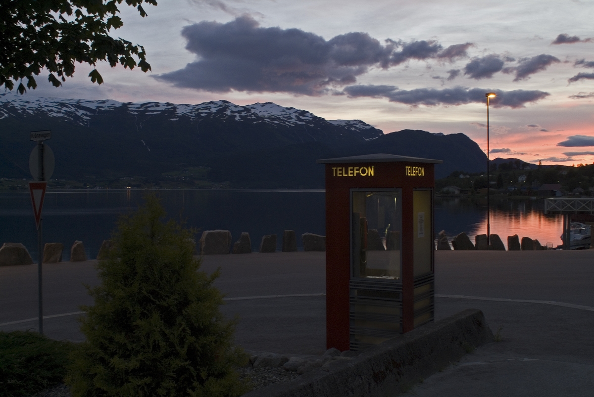 This is the story of how Norway’s most important conversation-space was designed by a young, freshly graduated man from Bergen.

“Norwegian architects are hereby invited…”
In the autumn of 1932, Oslo Telefonanlegginitiated an architectural competition. Finally, Oslo would get its own telephone booth. The city had had so called “talking-stations” from 1885, which in turn were overtaken by automatic telephones 
 only available at selected Narvesen kiosks. The state 
was of the opinion that now was the time to offer the public a better service; public telephone booths open 24/7, like the ones they already had in Sweden and England. But what would they look like, these new telephone booths? What considerations would it
 be necessary to take when designing it? The telegraph board developed a detailed list of demands and restraints: “The booth is intended to be placed outside on the streets and squares and need to be designed so that snow and ice does not hinder the opening and closing of the doors,” they wrote. “To prevent vandalism, theft, uncleanliness etc. inside the booth, it needs to be designed so that from all angles one may see what is going on in there.” Additionally, it would need to withstand storms and bad weather, and “preferably also being whipped by rain mixed with seawater” 

This was not all: The appearance would have to be «pleasing». The booth also needed to be movable, so that it could be taken in to be serviced at Telegrafverket’s main workshops. The reqired material was iron, and the surface was to be spray painted  preferably using car-body paint. There was a requirement for “a writing shelf, a pack shelf, and a suitable place for the telephone catalogue.” Also, there would need to be an illuminated TELEFON  sign, easily visible from all four angles. The total cost for each booth should not exceed 1000 kroner. The first prize for coming up with such a product was 800 kroner.

“Norwegianarchitects are hereby invited to partake in a competition for the design of a telephone booth…”  

The man with the solution
«At some point in 1932, Georg Fredrik sat at a party in Bergen. Maybe he felt a bit lost and forgotten as he often had throughout his life. He retreated to a quiet corner, took out a pencil and strted doodling on a matchbox.  According to my mother, this was how the telephone booth came into being.” In the book “Norges lille røde  historien om telefonkiosken,” Lars Fasting describes his father, the man who is far less known than the iconic architctural structure he left behind. Georg Fredrik Fasting was from Bergen, born into a family of working people and smallholders. One unusual facet of Georg Fredrik was that he was born without ears. His mother made sure he learnt to speak, read and write, 
ut Lars Fasting indicates that his father would seek refuge in drawing when the social challenges became too much to bear. And in the end drawing became his profession. In 1924 he secured a guarantor for a student loan, and started studying to become an a
rchitect at the NTH. Throughout the 1930s he entered several architectural competitions, with drafts produced, according to his son, “after work and in the late hours of the night.”

His efforts were not wasted. Out of 93 entries, with names such as “Flirt”, “Brrr”, “Ring” and “Amor”, the jury selected Fasting’s submission, “RIKS” as the new telephone booth: “The draft shows a strikingly simple solution to the task, technically as well as aesthetically well worked out.”

Taut and provident
Simple and aesthetc are the keywords here. Fasting had designed a booth pointing towards the future, and to modernism. Just how modern it was can be seen by comparing RIKS to the British telephone booth, also designed in the interwar-era. While the British version with it classicistic style is looking back to the heyday of the empire, Fasting’s booth is progressive and functionalistic. Like most Norwegian architects, Fasting broke with the classicistic style of architecture after the Stockholm-exhibition in 1930. “After it, almost all buildings erected in Norway until the German invasion in 1940, were in the functionalistic architectural style,” writes senior curator of architecture at the Norwegian National Museum, Ulf Grønvold, in the book, “Den lille røde”.“TheNorwegian booth is a piece of functionalistic architecture, an asymmetric composition with its roof slab overhanging the word TELEFON, in bold sans seraph lettering,”concludes Ulf Grønvold.

Fashionably red
And it was red. Fasting chose a colour which was part of the modern palette. “A bright red colour, but not as shiny as a signal red, the character of the colour places it among the fashionable colours within functionalism,” states paintings conservator and researcher in NIKU (Norwegian Institute for Cultural Heitage Research), Jon Brænne. In his opinion, Fasting went for visibility without making the booth stand out too much from its surroundings. The original colour was in use up to around 1950, when it changed to signal red. Towards the end of the 1970s the clour was again adjusted towards today’s orangey red.

The design, however, has not changed. RIKS is eighty years and still looks remarkably good. That’s what makes Fasting’s telephone booth a classic  even before it was added to DOCOMOMO’s list over moden icons of design. For Telenor, the telephone booth has served as a pathway into the hearts of the public. For many, Telenor (Televerket) was synonymous with exactly this telephone booth, because this was where one would go to place a call. Having a home
phone was not common until the 1980s. As such the red box became part of the Norwegian everyday and consciousness. The symbol- and publicity value of this is hard to evaluate, but in 2007 it was time to give honour where honour was due, Telenor, in consul
tation with the Directorate for Cultural Heritage, decided to preserve 100 telephone booths for all eternity.

And what about Georg Fredrik Fasting? What happened to him? At the age of 56 an entry in his diary states: «I CAN HEAR». As the first person in th world he had undergone an operation where he had ear canals constructed and eardrums fitted. For the rest of his life, the man behind Norway’s own telephone booth could answer the telephone himself.

Source: Norges lille røde historien om telefonkiosken (2007), issued by The Norwegian Telecom Museum and Telenor Cultural Heritage.