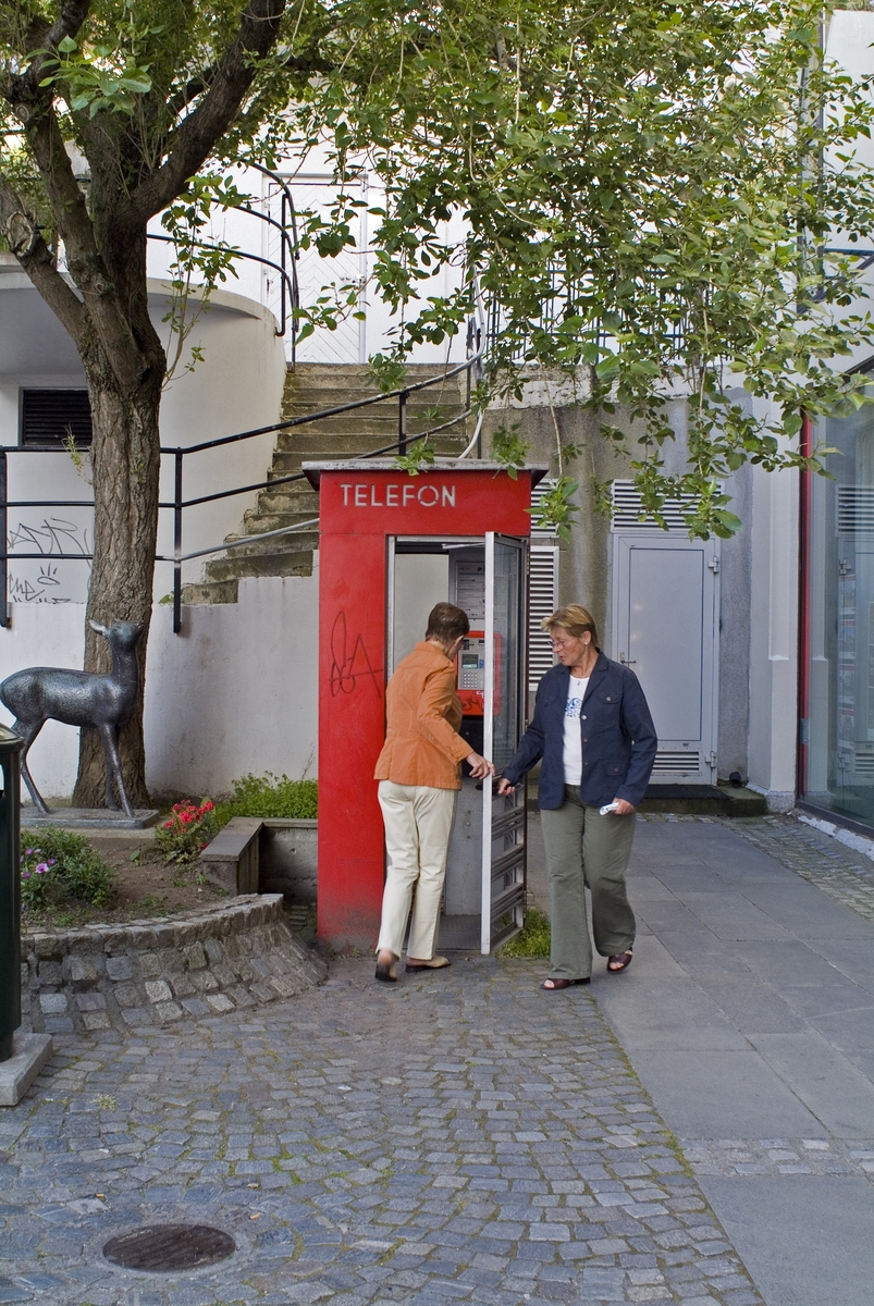 This is the story of how Norway’s most important conversation-space was designed by a young, freshly graduated man from Bergen.

“Norwegian architects are hereby invited…”
In the autumn of 1932, Oslo Telefonanlegginitiated an architectural competition. Finally, Oslo would get its own telephone booth. The city had had so called “talking-stations” from 1885, which in turn were overtaken by automatic telephones 
 only available at selected Narvesen kiosks. The state 
was of the opinion that now was the time to offer the public a better service; public telephone booths open 24/7, like the ones they already had in Sweden and England. But what would they look like, these new telephone booths? What considerations would it
 be necessary to take when designing it? The telegraph board developed a detailed list of demands and restraints: “The booth is intended to be placed outside on the streets and squares and need to be designed so that snow and ice does not hinder the opening and closing of the doors,” they wrote. “To prevent vandalism, theft, uncleanliness etc. inside the booth, it needs to be designed so that from all angles one may see what is going on in there.” Additionally, it would need to withstand storms and bad weather, and “preferably also being whipped by rain mixed with seawater” 

This was not all: The appearance would have to be «pleasing». The booth also needed to be movable, so that it could be taken in to be serviced at Telegrafverket’s main workshops. The reqired material was iron, and the surface was to be spray painted  preferably using car-body paint. There was a requirement for “a writing shelf, a pack shelf, and a suitable place for the telephone catalogue.” Also, there would need to be an illuminated TELEFON  sign, easily visible from all four angles. The total cost for each booth should not exceed 1000 kroner. The first prize for coming up with such a product was 800 kroner.

“Norwegianarchitects are hereby invited to partake in a competition for the design of a telephone booth…”  

The man with the solution
«At some point in 1932, Georg Fredrik sat at a party in Bergen. Maybe he felt a bit lost and forgotten as he often had throughout his life. He retreated to a quiet corner, took out a pencil and strted doodling on a matchbox.  According to my mother, this was how the telephone booth came into being.” In the book “Norges lille røde  historien om telefonkiosken,” Lars Fasting describes his father, the man who is far less known than the iconic architctural structure he left behind. Georg Fredrik Fasting was from Bergen, born into a family of working people and smallholders. One unusual facet of Georg Fredrik was that he was born without ears. His mother made sure he learnt to speak, read and write, 
ut Lars Fasting indicates that his father would seek refuge in drawing when the social challenges became too much to bear. And in the end drawing became his profession. In 1924 he secured a guarantor for a student loan, and started studying to become an a
rchitect at the NTH. Throughout the 1930s he entered several architectural competitions, with drafts produced, according to his son, “after work and in the late hours of the night.”

His efforts were not wasted. Out of 93 entries, with names such as “Flirt”, “Brrr”, “Ring” and “Amor”, the jury selected Fasting’s submission, “RIKS” as the new telephone booth: “The draft shows a strikingly simple solution to the task, technically as well as aesthetically well worked out.”

Taut and provident
Simple and aesthetc are the keywords here. Fasting had designed a booth pointing towards the future, and to modernism. Just how modern it was can be seen by comparing RIKS to the British telephone booth, also designed in the interwar-era. While the British version with it classicistic style is looking back to the heyday of the empire, Fasting’s booth is progressive and functionalistic. Like most Norwegian architects, Fasting broke with the classicistic style of architecture after the Stockholm-exhibition in 1930. “After it, almost all buildings erected in Norway until the German invasion in 1940, were in the functionalistic architectural style,” writes senior curator of architecture at the Norwegian National Museum, Ulf Grønvold, in the book, “Den lille røde”.“TheNorwegian booth is a piece of functionalistic architecture, an asymmetric composition with its roof slab overhanging the word TELEFON, in bold sans seraph lettering,”concludes Ulf Grønvold.

Fashionably red
And it was red. Fasting chose a colour which was part of the modern palette. “A bright red colour, but not as shiny as a signal red, the character of the colour places it among the fashionable colours within functionalism,” states paintings conservator and researcher in NIKU (Norwegian Institute for Cultural Heitage Research), Jon Brænne. In his opinion, Fasting went for visibility without making the booth stand out too much from its surroundings. The original colour was in use up to around 1950, when it changed to signal red. Towards the end of the 1970s the clour was again adjusted towards today’s orangey red.

The design, however, has not changed. RIKS is eighty years and still looks remarkably good. That’s what makes Fasting’s telephone booth a classic  even before it was added to DOCOMOMO’s list over moden icons of design. For Telenor, the telephone booth has served as a pathway into the hearts of the public. For many, Telenor (Televerket) was synonymous with exactly this telephone booth, because this was where one would go to place a call. Having a home
phone was not common until the 1980s. As such the red box became part of the Norwegian everyday and consciousness. The symbol- and publicity value of this is hard to evaluate, but in 2007 it was time to give honour where honour was due, Telenor, in consul
tation with the Directorate for Cultural Heritage, decided to preserve 100 telephone booths for all eternity.

And what about Georg Fredrik Fasting? What happened to him? At the age of 56 an entry in his diary states: «I CAN HEAR». As the first person in th world he had undergone an operation where he had ear canals constructed and eardrums fitted. For the rest of his life, the man behind Norway’s own telephone booth could answer the telephone himself.

Source: Norges lille røde historien om telefonkiosken (2007), issued by The Norwegian Telecom Museum and Telenor Cultural Heritage.
