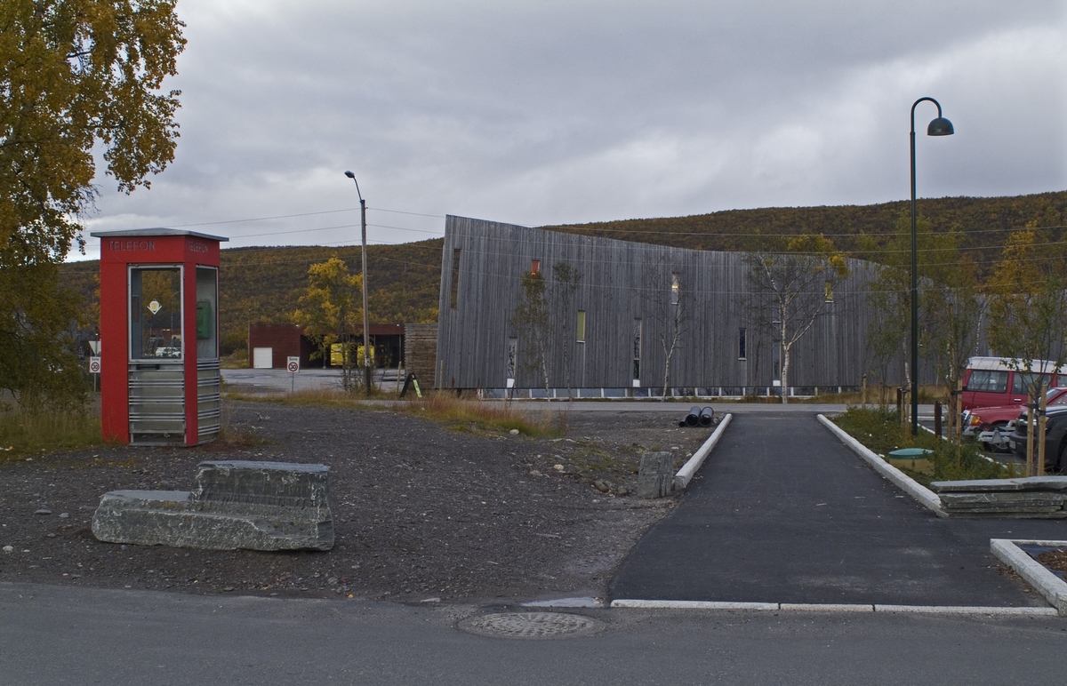 This is the story of how Norway’s most important conversation-space was designed by a young, freshly graduated man from Bergen.

“Norwegian architects are hereby invited…”
In the autumn of 1932, Oslo Telefonanlegginitiated an architectural competition. Finally, Oslo would get its own telephone booth. The city had had so called “talking-stations” from 1885, which in turn were overtaken by automatic telephones 
 only available at selected Narvesen kiosks. The state 
was of the opinion that now was the time to offer the public a better service; public telephone booths open 24/7, like the ones they already had in Sweden and England. But what would they look like, these new telephone booths? What considerations would it
 be necessary to take when designing it? The telegraph board developed a detailed list of demands and restraints: “The booth is intended to be placed outside on the streets and squares and need to be designed so that snow and ice does not hinder the opening and closing of the doors,” they wrote. “To prevent vandalism, theft, uncleanliness etc. inside the booth, it needs to be designed so that from all angles one may see what is going on in there.” Additionally, it would need to withstand storms and bad weather, and “preferably also being whipped by rain mixed with seawater” 

This was not all: The appearance would have to be «pleasing». The booth also needed to be movable, so that it could be taken in to be serviced at Telegrafverket’s main workshops. The reqired material was iron, and the surface was to be spray painted  preferably using car-body paint. There was a requirement for “a writing shelf, a pack shelf, and a suitable place for the telephone catalogue.” Also, there would need to be an illuminated TELEFON  sign, easily visible from all four angles. The total cost for each booth should not exceed 1000 kroner. The first prize for coming up with such a product was 800 kroner.

“Norwegianarchitects are hereby invited to partake in a competition for the design of a telephone booth…”  

The man with the solution
«At some point in 1932, Georg Fredrik sat at a party in Bergen. Maybe he felt a bit lost and forgotten as he often had throughout his life. He retreated to a quiet corner, took out a pencil and strted doodling on a matchbox.  According to my mother, this was how the telephone booth came into being.” In the book “Norges lille røde  historien om telefonkiosken,” Lars Fasting describes his father, the man who is far less known than the iconic architctural structure he left behind. Georg Fredrik Fasting was from Bergen, born into a family of working people and smallholders. One unusual facet of Georg Fredrik was that he was born without ears. His mother made sure he learnt to speak, read and write, 
ut Lars Fasting indicates that his father would seek refuge in drawing when the social challenges became too much to bear. And in the end drawing became his profession. In 1924 he secured a guarantor for a student loan, and started studying to become an a
rchitect at the NTH. Throughout the 1930s he entered several architectural competitions, with drafts produced, according to his son, “after work and in the late hours of the night.”

His efforts were not wasted. Out of 93 entries, with names such as “Flirt”, “Brrr”, “Ring” and “Amor”, the jury selected Fasting’s submission, “RIKS” as the new telephone booth: “The draft shows a strikingly simple solution to the task, technically as well as aesthetically well worked out.”

Taut and provident
Simple and aesthetc are the keywords here. Fasting had designed a booth pointing towards the future, and to modernism. Just how modern it was can be seen by comparing RIKS to the British telephone booth, also designed in the interwar-era. While the British version with it classicistic style is looking back to the heyday of the empire, Fasting’s booth is progressive and functionalistic. Like most Norwegian architects, Fasting broke with the classicistic style of architecture after the Stockholm-exhibition in 1930. “After it, almost all buildings erected in Norway until the German invasion in 1940, were in the functionalistic architectural style,” writes senior curator of architecture at the Norwegian National Museum, Ulf Grønvold, in the book, “Den lille røde”.“TheNorwegian booth is a piece of functionalistic architecture, an asymmetric composition with its roof slab overhanging the word TELEFON, in bold sans seraph lettering,”concludes Ulf Grønvold.

Fashionably red
And it was red. Fasting chose a colour which was part of the modern palette. “A bright red colour, but not as shiny as a signal red, the character of the colour places it among the fashionable colours within functionalism,” states paintings conservator and researcher in NIKU (Norwegian Institute for Cultural Heitage Research), Jon Brænne. In his opinion, Fasting went for visibility without making the booth stand out too much from its surroundings. The original colour was in use up to around 1950, when it changed to signal red. Towards the end of the 1970s the clour was again adjusted towards today’s orangey red.

The design, however, has not changed. RIKS is eighty years and still looks remarkably good. That’s what makes Fasting’s telephone booth a classic  even before it was added to DOCOMOMO’s list over moden icons of design. For Telenor, the telephone booth has served as a pathway into the hearts of the public. For many, Telenor (Televerket) was synonymous with exactly this telephone booth, because this was where one would go to place a call. Having a home
phone was not common until the 1980s. As such the red box became part of the Norwegian everyday and consciousness. The symbol- and publicity value of this is hard to evaluate, but in 2007 it was time to give honour where honour was due, Telenor, in consul
tation with the Directorate for Cultural Heritage, decided to preserve 100 telephone booths for all eternity.

And what about Georg Fredrik Fasting? What happened to him? At the age of 56 an entry in his diary states: «I CAN HEAR». As the first person in th world he had undergone an operation where he had ear canals constructed and eardrums fitted. For the rest of his life, the man behind Norway’s own telephone booth could answer the telephone himself.

Source: Norges lille røde historien om telefonkiosken (2007), issued by The Norwegian Telecom Museum and Telenor Cultural Heritage.
