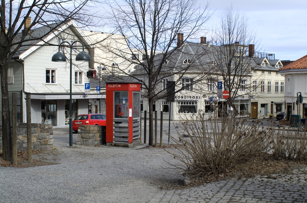 This is the story of how Norway’s most important conversation-space was designed by a young, freshly graduated man from Bergen.

“Norwegian architects are hereby invited…”
In the autumn of 1932, Oslo Telefonanlegginitiated an architectural competition. Finally, Oslo would get its own telephone booth. The city had had so called “talking-stations” from 1885, which in turn were overtaken by automatic telephones 
 only available at selected Narvesen kiosks. The state 
was of the opinion that now was the time to offer the public a better service; public telephone booths open 24/7, like the ones they already had in Sweden and England. But what would they look like, these new telephone booths? What considerations would it
 be necessary to take when designing it? The telegraph board developed a detailed list of demands and restraints: “The booth is intended to be placed outside on the streets and squares and need to be designed so that snow and ice does not hinder the opening and closing of the doors,” they wrote. “To prevent vandalism, theft, uncleanliness etc. inside the booth, it needs to be designed so that from all angles one may see what is going on in there.” Additionally, it would need to withstand storms and bad weather, and “preferably also being whipped by rain mixed with seawater” 

This was not all: The appearance would have to be «pleasing». The booth also needed to be movable, so that it could be taken in to be serviced at Telegrafverket’s main workshops. The reqired material was iron, and the surface was to be spray painted  preferably using car-body paint. There was a requirement for “a writing shelf, a pack shelf, and a suitable place for the telephone catalogue.” Also, there would need to be an illuminated TELEFON  sign, easily visible from all four angles. The total cost for each booth should not exceed 1000 kroner. The first prize for coming up with such a product was 800 kroner.

“Norwegianarchitects are hereby invited to partake in a competition for the design of a telephone booth…”  

The man with the solution
«At some point in 1932, Georg Fredrik sat at a party in Bergen. Maybe he felt a bit lost and forgotten as he often had throughout his life. He retreated to a quiet corner, took out a pencil and strted doodling on a matchbox.  According to my mother, this was how the telephone booth came into being.” In the book “Norges lille røde  historien om telefonkiosken,” Lars Fasting describes his father, the man who is far less known than the iconic architctural structure he left behind. Georg Fredrik Fasting was from Bergen, born into a family of working people and smallholders. One unusual facet of Georg Fredrik was that he was born without ears. His mother made sure he learnt to speak, read and write, 
ut Lars Fasting indicates that his father would seek refuge in drawing when the social challenges became too much to bear. And in the end drawing became his profession. In 1924 he secured a guarantor for a student loan, and started studying to become an a
rchitect at the NTH. Throughout the 1930s he entered several architectural competitions, with drafts produced, according to his son, “after work and in the late hours of the night.”

His efforts were not wasted. Out of 93 entries, with names such as “Flirt”, “Brrr”, “Ring” and “Amor”, the jury selected Fasting’s submission, “RIKS” as the new telephone booth: “The draft shows a strikingly simple solution to the task, technically as well as aesthetically well worked out.”

Taut and provident
Simple and aesthetc are the keywords here. Fasting had designed a booth pointing towards the future, and to modernism. Just how modern it was can be seen by comparing RIKS to the British telephone booth, also designed in the interwar-era. While the British version with it classicistic style is looking back to the heyday of the empire, Fasting’s booth is progressive and functionalistic. Like most Norwegian architects, Fasting broke with the classicistic style of architecture after the Stockholm-exhibition in 1930. “After it, almost all buildings erected in Norway until the German invasion in 1940, were in the functionalistic architectural style,” writes senior curator of architecture at the Norwegian National Museum, Ulf Grønvold, in the book, “Den lille røde”.“TheNorwegian booth is a piece of functionalistic architecture, an asymmetric composition with its roof slab overhanging the word TELEFON, in bold sans seraph lettering,”concludes Ulf Grønvold.

Fashionably red
And it was red. Fasting chose a colour which was part of the modern palette. “A bright red colour, but not as shiny as a signal red, the character of the colour places it among the fashionable colours within functionalism,” states paintings conservator and researcher in NIKU (Norwegian Institute for Cultural Heitage Research), Jon Brænne. In his opinion, Fasting went for visibility without making the booth stand out too much from its surroundings. The original colour was in use up to around 1950, when it changed to signal red. Towards the end of the 1970s the clour was again adjusted towards today’s orangey red.

The design, however, has not changed. RIKS is eighty years and still looks remarkably good. That’s what makes Fasting’s telephone booth a classic  even before it was added to DOCOMOMO’s list over moden icons of design. For Telenor, the telephone booth has served as a pathway into the hearts of the public. For many, Telenor (Televerket) was synonymous with exactly this telephone booth, because this was where one would go to place a call. Having a home
phone was not common until the 1980s. As such the red box became part of the Norwegian everyday and consciousness. The symbol- and publicity value of this is hard to evaluate, but in 2007 it was time to give honour where honour was due, Telenor, in consul
tation with the Directorate for Cultural Heritage, decided to preserve 100 telephone booths for all eternity.

And what about Georg Fredrik Fasting? What happened to him? At the age of 56 an entry in his diary states: «I CAN HEAR». As the first person in th world he had undergone an operation where he had ear canals constructed and eardrums fitted. For the rest of his life, the man behind Norway’s own telephone booth could answer the telephone himself.

Source: Norges lille røde historien om telefonkiosken (2007), issued by The Norwegian Telecom Museum and Telenor Cultural Heritage.