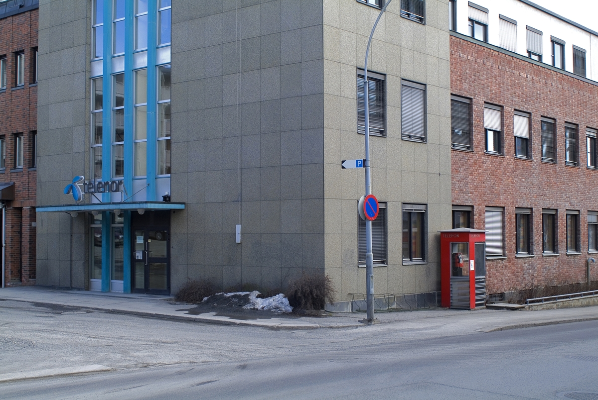 This is the story of how Norway’s most important conversation-space was designed by a young, freshly graduated man from Bergen.

“Norwegian architects are hereby invited…”
In the autumn of 1932, Oslo Telefonanlegginitiated an architectural competition. Finally, Oslo would get its own telephone booth. The city had had so called “talking-stations” from 1885, which in turn were overtaken by automatic telephones 
 only available at selected Narvesen kiosks. The state 
was of the opinion that now was the time to offer the public a better service; public telephone booths open 24/7, like the ones they already had in Sweden and England. But what would they look like, these new telephone booths? What considerations would it
 be necessary to take when designing it? The telegraph board developed a detailed list of demands and restraints: “The booth is intended to be placed outside on the streets and squares and need to be designed so that snow and ice does not hinder the opening and closing of the doors,” they wrote. “To prevent vandalism, theft, uncleanliness etc. inside the booth, it needs to be designed so that from all angles one may see what is going on in there.” Additionally, it would need to withstand storms and bad weather, and “preferably also being whipped by rain mixed with seawater” 

This was not all: The appearance would have to be «pleasing». The booth also needed to be movable, so that it could be taken in to be serviced at Telegrafverket’s main workshops. The reqired material was iron, and the surface was to be spray painted  preferably using car-body paint. There was a requirement for “a writing shelf, a pack shelf, and a suitable place for the telephone catalogue.” Also, there would need to be an illuminated TELEFON  sign, easily visible from all four angles. The total cost for each booth should not exceed 1000 kroner. The first prize for coming up with such a product was 800 kroner.

“Norwegianarchitects are hereby invited to partake in a competition for the design of a telephone booth…”  

The man with the solution
«At some point in 1932, Georg Fredrik sat at a party in Bergen. Maybe he felt a bit lost and forgotten as he often had throughout his life. He retreated to a quiet corner, took out a pencil and strted doodling on a matchbox.  According to my mother, this was how the telephone booth came into being.” In the book “Norges lille røde  historien om telefonkiosken,” Lars Fasting describes his father, the man who is far less known than the iconic architctural structure he left behind. Georg Fredrik Fasting was from Bergen, born into a family of working people and smallholders. One unusual facet of Georg Fredrik was that he was born without ears. His mother made sure he learnt to speak, read and write, 
ut Lars Fasting indicates that his father would seek refuge in drawing when the social challenges became too much to bear. And in the end drawing became his profession. In 1924 he secured a guarantor for a student loan, and started studying to become an a
rchitect at the NTH. Throughout the 1930s he entered several architectural competitions, with drafts produced, according to his son, “after work and in the late hours of the night.”

His efforts were not wasted. Out of 93 entries, with names such as “Flirt”, “Brrr”, “Ring” and “Amor”, the jury selected Fasting’s submission, “RIKS” as the new telephone booth: “The draft shows a strikingly simple solution to the task, technically as well as aesthetically well worked out.”

Taut and provident
Simple and aesthetc are the keywords here. Fasting had designed a booth pointing towards the future, and to modernism. Just how modern it was can be seen by comparing RIKS to the British telephone booth, also designed in the interwar-era. While the British version with it classicistic style is looking back to the heyday of the empire, Fasting’s booth is progressive and functionalistic. Like most Norwegian architects, Fasting broke with the classicistic style of architecture after the Stockholm-exhibition in 1930. “After it, almost all buildings erected in Norway until the German invasion in 1940, were in the functionalistic architectural style,” writes senior curator of architecture at the Norwegian National Museum, Ulf Grønvold, in the book, “Den lille røde”.“TheNorwegian booth is a piece of functionalistic architecture, an asymmetric composition with its roof slab overhanging the word TELEFON, in bold sans seraph lettering,”concludes Ulf Grønvold.

Fashionably red
And it was red. Fasting chose a colour which was part of the modern palette. “A bright red colour, but not as shiny as a signal red, the character of the colour places it among the fashionable colours within functionalism,” states paintings conservator and researcher in NIKU (Norwegian Institute for Cultural Heitage Research), Jon Brænne. In his opinion, Fasting went for visibility without making the booth stand out too much from its surroundings. The original colour was in use up to around 1950, when it changed to signal red. Towards the end of the 1970s the clour was again adjusted towards today’s orangey red.

The design, however, has not changed. RIKS is eighty years and still looks remarkably good. That’s what makes Fasting’s telephone booth a classic  even before it was added to DOCOMOMO’s list over moden icons of design. For Telenor, the telephone booth has served as a pathway into the hearts of the public. For many, Telenor (Televerket) was synonymous with exactly this telephone booth, because this was where one would go to place a call. Having a home
phone was not common until the 1980s. As such the red box became part of the Norwegian everyday and consciousness. The symbol- and publicity value of this is hard to evaluate, but in 2007 it was time to give honour where honour was due, Telenor, in consul
tation with the Directorate for Cultural Heritage, decided to preserve 100 telephone booths for all eternity.

And what about Georg Fredrik Fasting? What happened to him? At the age of 56 an entry in his diary states: «I CAN HEAR». As the first person in th world he had undergone an operation where he had ear canals constructed and eardrums fitted. For the rest of his life, the man behind Norway’s own telephone booth could answer the telephone himself.

Source: Norges lille røde historien om telefonkiosken (2007), issued by The Norwegian Telecom Museum and Telenor Cultural Heritage.
