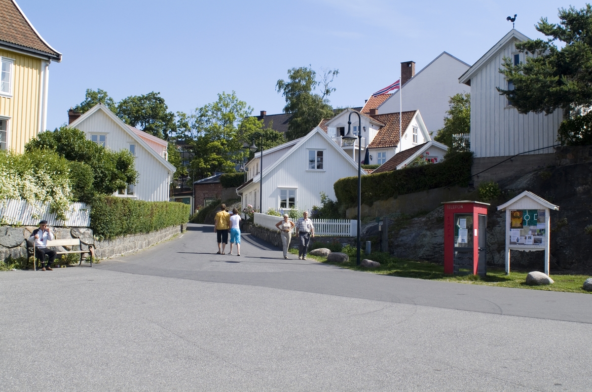 This is the story of how Norway’s most important conversation-space was designed by a young, freshly graduated man from Bergen.

“Norwegian architects are hereby invited…”
In the autumn of 1932, Oslo Telefonanlegginitiated an architectural competition. Finally, Oslo would get its own telephone booth. The city had had so called “talking-stations” from 1885, which in turn were overtaken by automatic telephones 
 only available at selected Narvesen kiosks. The state 
was of the opinion that now was the time to offer the public a better service; public telephone booths open 24/7, like the ones they already had in Sweden and England. But what would they look like, these new telephone booths? What considerations would it
 be necessary to take when designing it? The telegraph board developed a detailed list of demands and restraints: “The booth is intended to be placed outside on the streets and squares and need to be designed so that snow and ice does not hinder the opening and closing of the doors,” they wrote. “To prevent vandalism, theft, uncleanliness etc. inside the booth, it needs to be designed so that from all angles one may see what is going on in there.” Additionally, it would need to withstand storms and bad weather, and “preferably also being whipped by rain mixed with seawater” 

This was not all: The appearance would have to be «pleasing». The booth also needed to be movable, so that it could be taken in to be serviced at Telegrafverket’s main workshops. The reqired material was iron, and the surface was to be spray painted  preferably using car-body paint. There was a requirement for “a writing shelf, a pack shelf, and a suitable place for the telephone catalogue.” Also, there would need to be an illuminated TELEFON  sign, easily visible from all four angles. The total cost for each booth should not exceed 1000 kroner. The first prize for coming up with such a product was 800 kroner.

“Norwegianarchitects are hereby invited to partake in a competition for the design of a telephone booth…”  

The man with the solution
«At some point in 1932, Georg Fredrik sat at a party in Bergen. Maybe he felt a bit lost and forgotten as he often had throughout his life. He retreated to a quiet corner, took out a pencil and strted doodling on a matchbox.  According to my mother, this was how the telephone booth came into being.” In the book “Norges lille røde  historien om telefonkiosken,” Lars Fasting describes his father, the man who is far less known than the iconic architctural structure he left behind. Georg Fredrik Fasting was from Bergen, born into a family of working people and smallholders. One unusual facet of Georg Fredrik was that he was born without ears. His mother made sure he learnt to speak, read and write, 
ut Lars Fasting indicates that his father would seek refuge in drawing when the social challenges became too much to bear. And in the end drawing became his profession. In 1924 he secured a guarantor for a student loan, and started studying to become an a
rchitect at the NTH. Throughout the 1930s he entered several architectural competitions, with drafts produced, according to his son, “after work and in the late hours of the night.”

His efforts were not wasted. Out of 93 entries, with names such as “Flirt”, “Brrr”, “Ring” and “Amor”, the jury selected Fasting’s submission, “RIKS” as the new telephone booth: “The draft shows a strikingly simple solution to the task, technically as well as aesthetically well worked out.”

Taut and provident
Simple and aesthetc are the keywords here. Fasting had designed a booth pointing towards the future, and to modernism. Just how modern it was can be seen by comparing RIKS to the British telephone booth, also designed in the interwar-era. While the British version with it classicistic style is looking back to the heyday of the empire, Fasting’s booth is progressive and functionalistic. Like most Norwegian architects, Fasting broke with the classicistic style of architecture after the Stockholm-exhibition in 1930. “After it, almost all buildings erected in Norway until the German invasion in 1940, were in the functionalistic architectural style,” writes senior curator of architecture at the Norwegian National Museum, Ulf Grønvold, in the book, “Den lille røde”.“TheNorwegian booth is a piece of functionalistic architecture, an asymmetric composition with its roof slab overhanging the word TELEFON, in bold sans seraph lettering,”concludes Ulf Grønvold.

Fashionably red
And it was red. Fasting chose a colour which was part of the modern palette. “A bright red colour, but not as shiny as a signal red, the character of the colour places it among the fashionable colours within functionalism,” states paintings conservator and researcher in NIKU (Norwegian Institute for Cultural Heitage Research), Jon Brænne. In his opinion, Fasting went for visibility without making the booth stand out too much from its surroundings. The original colour was in use up to around 1950, when it changed to signal red. Towards the end of the 1970s the clour was again adjusted towards today’s orangey red.

The design, however, has not changed. RIKS is eighty years and still looks remarkably good. That’s what makes Fasting’s telephone booth a classic  even before it was added to DOCOMOMO’s list over moden icons of design. For Telenor, the telephone booth has served as a pathway into the hearts of the public. For many, Telenor (Televerket) was synonymous with exactly this telephone booth, because this was where one would go to place a call. Having a home
phone was not common until the 1980s. As such the red box became part of the Norwegian everyday and consciousness. The symbol- and publicity value of this is hard to evaluate, but in 2007 it was time to give honour where honour was due, Telenor, in consul
tation with the Directorate for Cultural Heritage, decided to preserve 100 telephone booths for all eternity.

And what about Georg Fredrik Fasting? What happened to him? At the age of 56 an entry in his diary states: «I CAN HEAR». As the first person in th world he had undergone an operation where he had ear canals constructed and eardrums fitted. For the rest of his life, the man behind Norway’s own telephone booth could answer the telephone himself.

Source: Norges lille røde historien om telefonkiosken (2007), issued by The Norwegian Telecom Museum and Telenor Cultural Heritage.