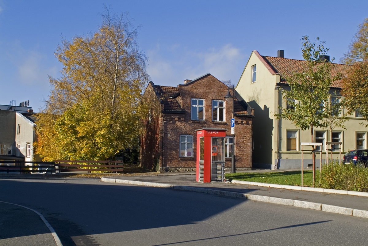 This is the story of how Norway’s most important conversation-space was designed by a young, freshly graduated man from Bergen.

“Norwegian architects are hereby invited…”
In the autumn of 1932, Oslo Telefonanlegginitiated an architectural competition. Finally, Oslo would get its own telephone booth. The city had had so called “talking-stations” from 1885, which in turn were overtaken by automatic telephones 
 only available at selected Narvesen kiosks. The state 
was of the opinion that now was the time to offer the public a better service; public telephone booths open 24/7, like the ones they already had in Sweden and England. But what would they look like, these new telephone booths? What considerations would it
 be necessary to take when designing it? The telegraph board developed a detailed list of demands and restraints: “The booth is intended to be placed outside on the streets and squares and need to be designed so that snow and ice does not hinder the opening and closing of the doors,” they wrote. “To prevent vandalism, theft, uncleanliness etc. inside the booth, it needs to be designed so that from all angles one may see what is going on in there.” Additionally, it would need to withstand storms and bad weather, and “preferably also being whipped by rain mixed with seawater” 

This was not all: The appearance would have to be «pleasing». The booth also needed to be movable, so that it could be taken in to be serviced at Telegrafverket’s main workshops. The reqired material was iron, and the surface was to be spray painted  preferably using car-body paint. There was a requirement for “a writing shelf, a pack shelf, and a suitable place for the telephone catalogue.” Also, there would need to be an illuminated TELEFON  sign, easily visible from all four angles. The total cost for each booth should not exceed 1000 kroner. The first prize for coming up with such a product was 800 kroner.

“Norwegianarchitects are hereby invited to partake in a competition for the design of a telephone booth…”  

The man with the solution
«At some point in 1932, Georg Fredrik sat at a party in Bergen. Maybe he felt a bit lost and forgotten as he often had throughout his life. He retreated to a quiet corner, took out a pencil and strted doodling on a matchbox.  According to my mother, this was how the telephone booth came into being.” In the book “Norges lille røde  historien om telefonkiosken,” Lars Fasting describes his father, the man who is far less known than the iconic architctural structure he left behind. Georg Fredrik Fasting was from Bergen, born into a family of working people and smallholders. One unusual facet of Georg Fredrik was that he was born without ears. His mother made sure he learnt to speak, read and write, 
ut Lars Fasting indicates that his father would seek refuge in drawing when the social challenges became too much to bear. And in the end drawing became his profession. In 1924 he secured a guarantor for a student loan, and started studying to become an a
rchitect at the NTH. Throughout the 1930s he entered several architectural competitions, with drafts produced, according to his son, “after work and in the late hours of the night.”

His efforts were not wasted. Out of 93 entries, with names such as “Flirt”, “Brrr”, “Ring” and “Amor”, the jury selected Fasting’s submission, “RIKS” as the new telephone booth: “The draft shows a strikingly simple solution to the task, technically as well as aesthetically well worked out.”

Taut and provident
Simple and aesthetc are the keywords here. Fasting had designed a booth pointing towards the future, and to modernism. Just how modern it was can be seen by comparing RIKS to the British telephone booth, also designed in the interwar-era. While the British version with it classicistic style is looking back to the heyday of the empire, Fasting’s booth is progressive and functionalistic. Like most Norwegian architects, Fasting broke with the classicistic style of architecture after the Stockholm-exhibition in 1930. “After it, almost all buildings erected in Norway until the German invasion in 1940, were in the functionalistic architectural style,” writes senior curator of architecture at the Norwegian National Museum, Ulf Grønvold, in the book, “Den lille røde”.“TheNorwegian booth is a piece of functionalistic architecture, an asymmetric composition with its roof slab overhanging the word TELEFON, in bold sans seraph lettering,”concludes Ulf Grønvold.

Fashionably red
And it was red. Fasting chose a colour which was part of the modern palette. “A bright red colour, but not as shiny as a signal red, the character of the colour places it among the fashionable colours within functionalism,” states paintings conservator and researcher in NIKU (Norwegian Institute for Cultural Heitage Research), Jon Brænne. In his opinion, Fasting went for visibility without making the booth stand out too much from its surroundings. The original colour was in use up to around 1950, when it changed to signal red. Towards the end of the 1970s the clour was again adjusted towards today’s orangey red.

The design, however, has not changed. RIKS is eighty years and still looks remarkably good. That’s what makes Fasting’s telephone booth a classic  even before it was added to DOCOMOMO’s list over moden icons of design. For Telenor, the telephone booth has served as a pathway into the hearts of the public. For many, Telenor (Televerket) was synonymous with exactly this telephone booth, because this was where one would go to place a call. Having a home
phone was not common until the 1980s. As such the red box became part of the Norwegian everyday and consciousness. The symbol- and publicity value of this is hard to evaluate, but in 2007 it was time to give honour where honour was due, Telenor, in consul
tation with the Directorate for Cultural Heritage, decided to preserve 100 telephone booths for all eternity.

And what about Georg Fredrik Fasting? What happened to him? At the age of 56 an entry in his diary states: «I CAN HEAR». As the first person in th world he had undergone an operation where he had ear canals constructed and eardrums fitted. For the rest of his life, the man behind Norway’s own telephone booth could answer the telephone himself.

Source: Norges lille røde historien om telefonkiosken (2007), issued by The Norwegian Telecom Museum and Telenor Cultural Heritage.