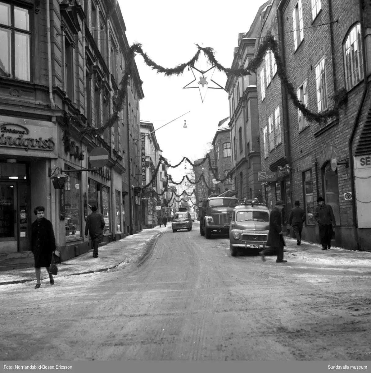 Nybrogatan i Sundsvall med bland annat frukthandlare Berg och olika butiker och hotell utmed gatan. Fotograferat för Nybrogatans Allehanda.