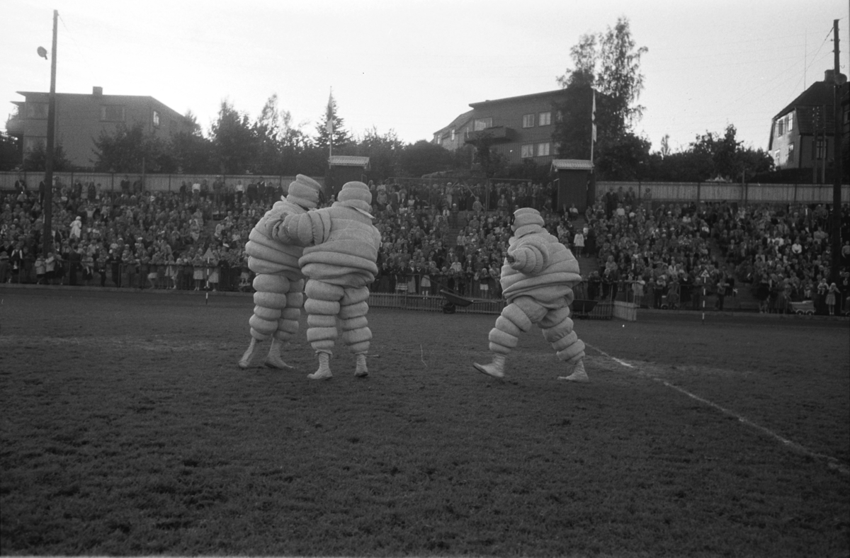 Diverse foto fra Barnas dag. Opptog i byen og aktiviteter på Hamar stadion. "Brytekamp" på Hamar stadion mellom tre voksne, "Michelinmenn". Mye publikum på tribunene.