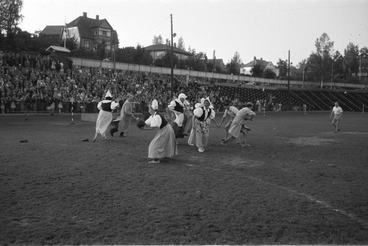 Diverse foto fra Barnas dag. Opptog i byen og aktiviteter på Hamar stadion. Utkledde kvinner og menn i ballspill på Hamar stadion. Kvinnelag og herrelag. Mye publikum på rinunene. Bolighus i bakgrunnen.