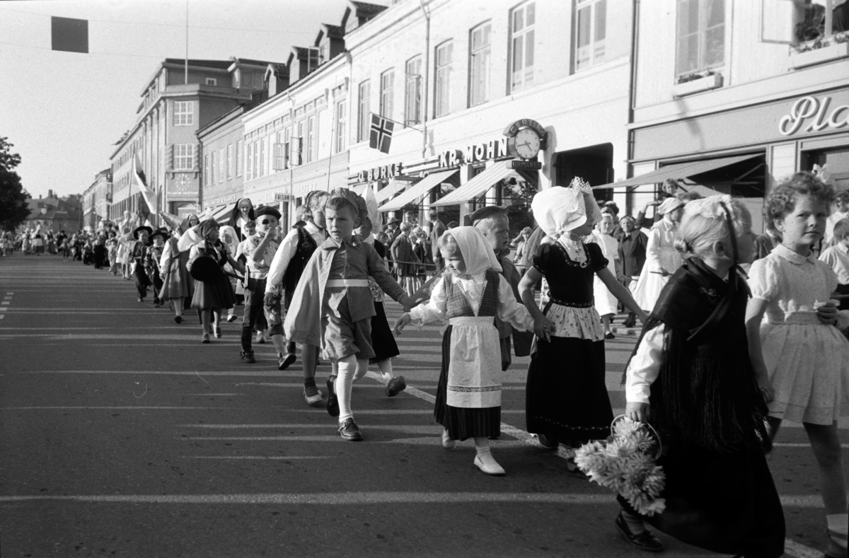 Diverse foto fra Barnas dag. Opptog i byen og aktiviteter på Hamar stadion.  Barn i kostymer går i tog i Strandgata, Hamar. Mye folk i gata.