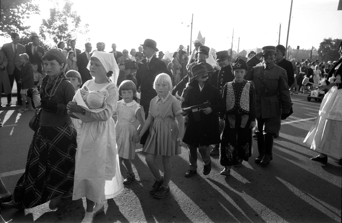 Diverse foto fra Barnas dag. Opptog i byen og aktiviteter på Hamar stadion. Barn i kostymer går i tog i Strandgata, Hamar. Mye publikum langs gata.