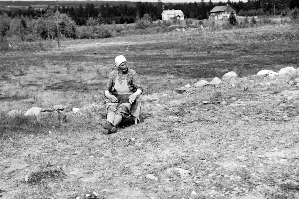 Mina Lunde (1885-1967) i Ilstad (87/9). I bakgrunnen ser vi husa i Rustad. Bildet er tatt i 1965.
