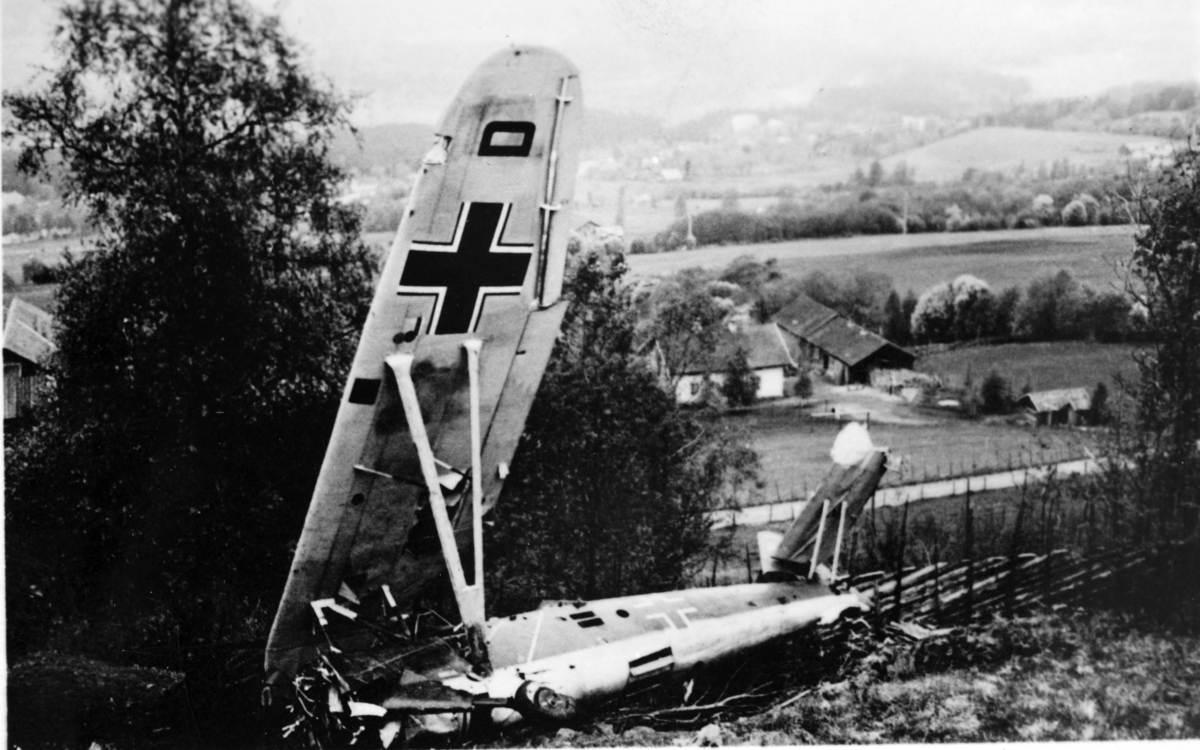 Tysk flyvrak, med skigard og gårdsbebyggelse i bakgrunnen.