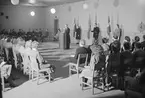 Lottainvigningen på F 3 Östgöta flygflottilj, 1948. Ceremoni inomhus, med musikkår, lottor och deltagare. En präst står i talarstolen.