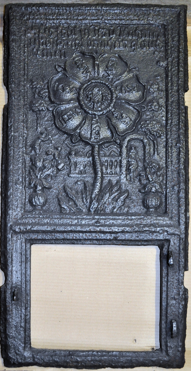 Fra protokollen (R. Berge):
Omn i ei høgd (botnplate vantar) med støypemynster i barok. Bakplata hev øvst denne innskrifti: "Alles thut in Jesu Nahm" "und so reths(?) drauf ein glaube Amen". 
Under denne ein stor sjaubladd blom, i kvart krunblad ordet: IESVS, i blomcentrum bokstavane A.M.E.N. Under blomen ymse motiv. Under desse att innskrifti: "Jesu beistand in der (Arbeit Jeder tag sein) Arbeit hat die uns mühel(?) früh und spät soll sie men von statten(?) gehen So müss Jesus bei dir stehen."
ST Anno (Jahr)  MT 1668 (Aarst. utydelegt).
Framstamnen som bakstamnen, men vantar alt som er nedanfor blomen.
Langsidune hev eit stort landskap, med ein islagd kanal(?), der ein mann gjeng paa (is)styltrur; han hev mist den eine og held paa aa dette i koll. Bak honom paa isen ser ein folk skuvar kvarandre paa kjolke. Bak kanalen landskap. Ikring bilætet er ei raame av baroksveivar. Yvi raama er ei innskrift, som luar: "Wer will närsisch(?) grösser sein Schadt ihm (je?) ... legt umehr ein."
Under bilætet au tysk innskrift, men støypingi er paa baae platune so utydeleg at ein fær kje samanheng i ho. 
Hyrneskinune vantar.