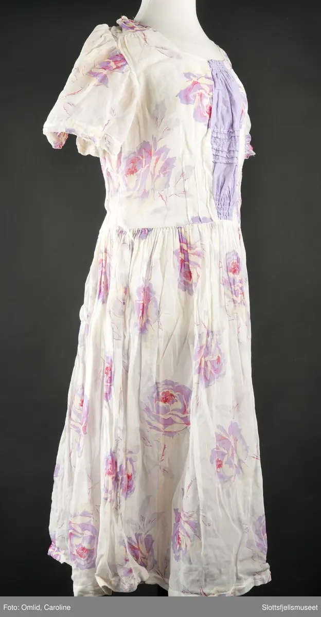 Hvit med lilla blomster. Omsydd under krigen. Trykknapper bak