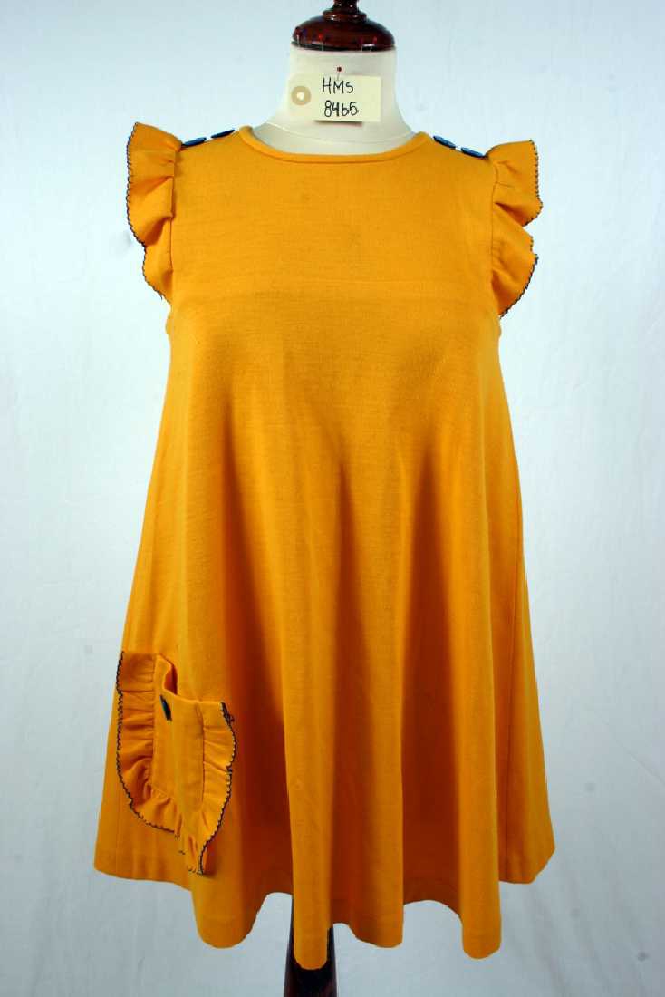 gul, kort, ermeløs kjole A-form, glidelås i rygg, blå knapper som dekor på skuldre, påsydd lomme med volang og knapp foran. 