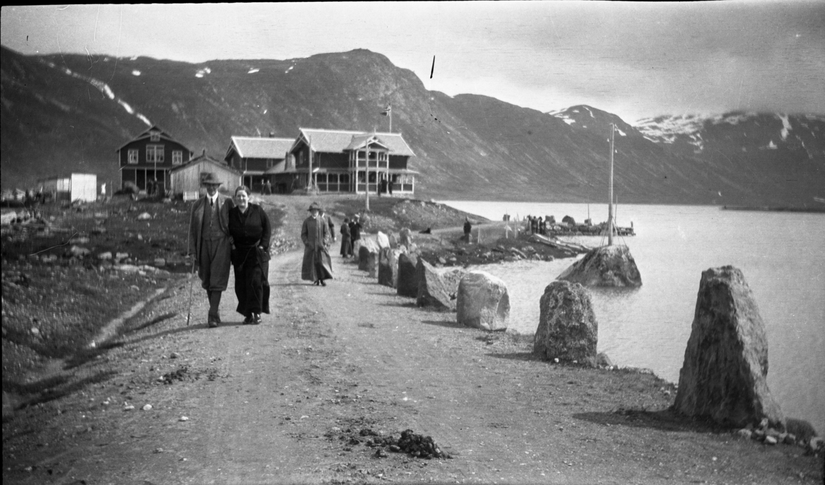 Fotoarkivet etter Gunnar Knudsen. Mennesker på fjelltur. Hotell/gjestgiveri i laft- og sveitserarkitektur. Hotellet har elektrisitet, (viser til stolpene) Bildet er tatt mellom 1910-1920.
PS. Hestelort i forgrunnen.