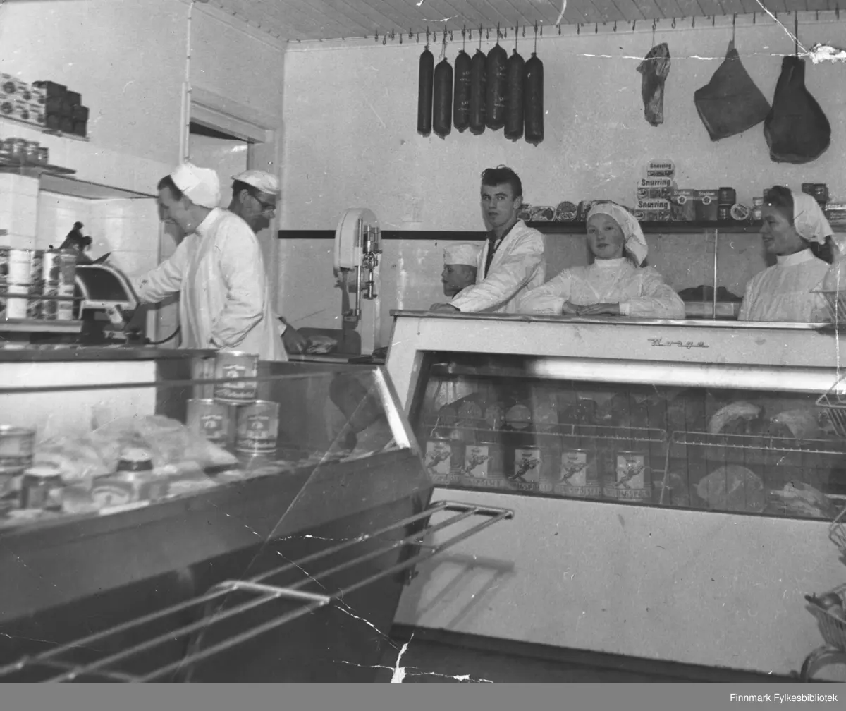 Fiskematforretning i Kjøllefjord, ca. 1962. Mannen med briller er innehaveren Edward Lund. Edwards kone Emmy står til venstre på bildet ved siden av Edward. De fire andre er fra venstre: Nils-Johan Lund, Even Herman Lund, Liv Lyngedal og Sigrunn Pedersen.