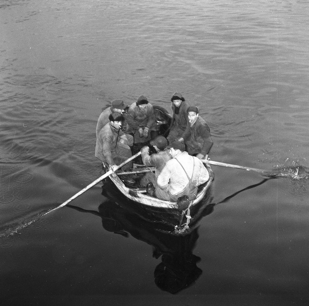 Magne Iversen s båtlag ved hjemkomst etter døgn i havsnød ca. 20.1.1956. 
Lisbeth Iversen skriver:  Denne hendelsen var med båten Syren *). eid av min farfar Magne Iversen. Med som mannskap var bl.a. sønnene Hans og Henry. De gikk ut om morgenen, det var høst og bra vær. Langt til havs fikk de notohavari. Det var mange båter i området, men de var litt langt unna. De laget fakler/nødbluss ved å dyppe tvist i olje, bundet til bambusstenger. Flere båter passerte da de var på landtur. Lyset fra de tente faklene var ikke nok til at de ble oppdaget. Det ble etterhvert igangsatt en leteaksjon, og etter et døgn ble de funnet. Da hadde de rekt langt nordover.
Seinere opplysning: Hendelsen er riktig, men båtens navn var M/K Bjørnulf. Mannskap f.v.: Harry Mikalsen, Karl Solvoll, Magne Iversen, Toralf Guldbrandsen, Hans Iversen, rormann Gunnar Iversen og Henry Iversen.