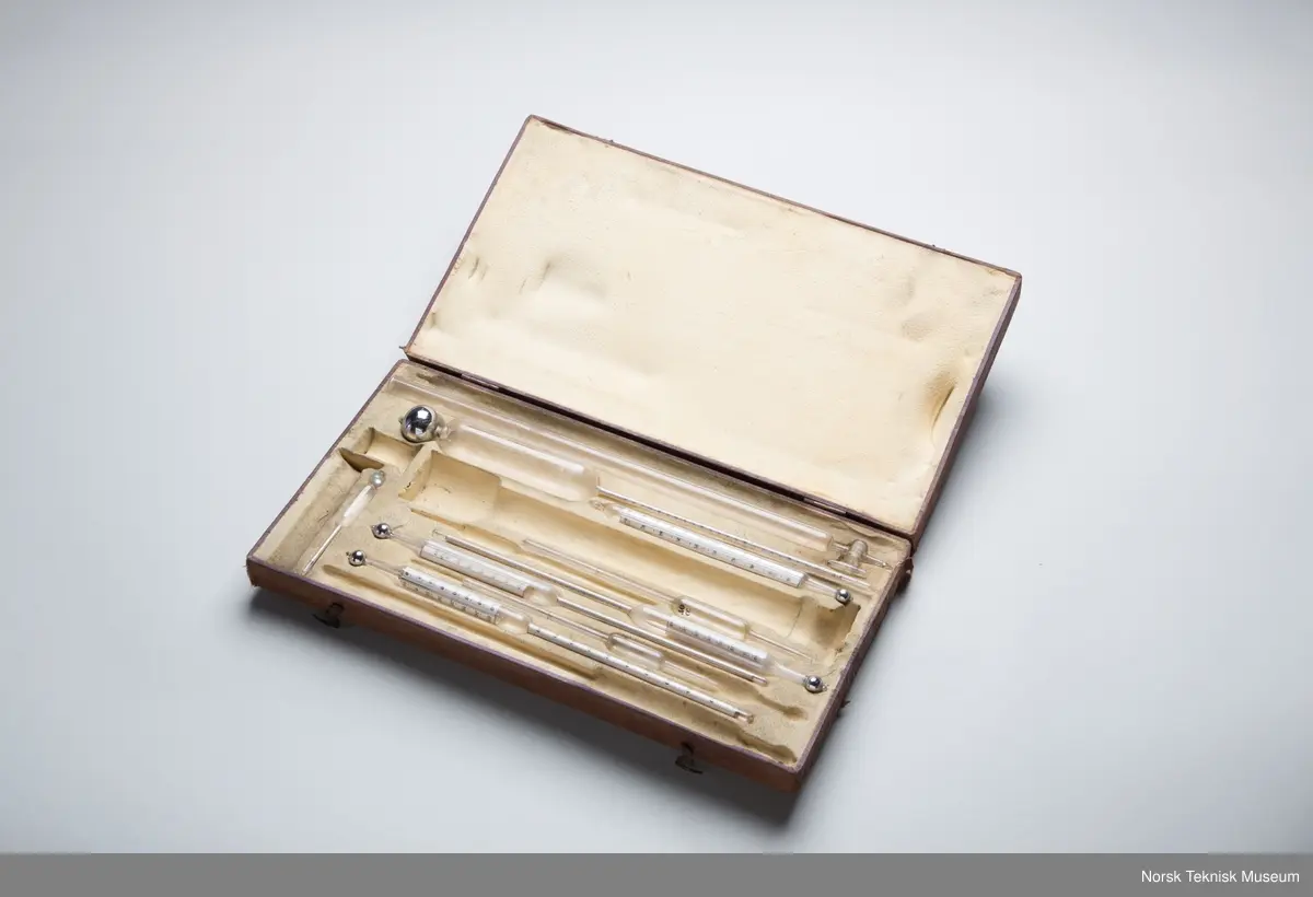 Ni deler av ulike termometer og pipetter i ulik  størrelse. I eske.