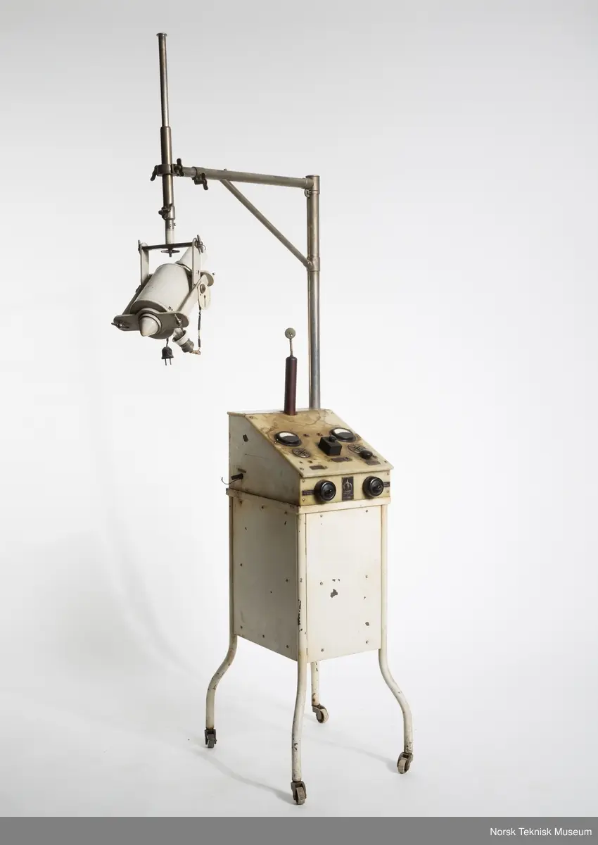 Venstre instrument går til 6 A, antagelig for primærstrømmen til transformatoren. Høyre instrument går til 2 A, antagelig for glødestrøm til røret. Venstre side "Heizanschluss". Høyre side "Heizanschluss für Röhre." Med transformator i oljebeholder og separat hammeravbryter. Vinkelrør med Edison sokkel sitter i trebeholder foret med blygummi og fastspent i svamåegummi. Røret sitter så fast i den stive gummien at det ikke lar seg gjøre å ta den ut.