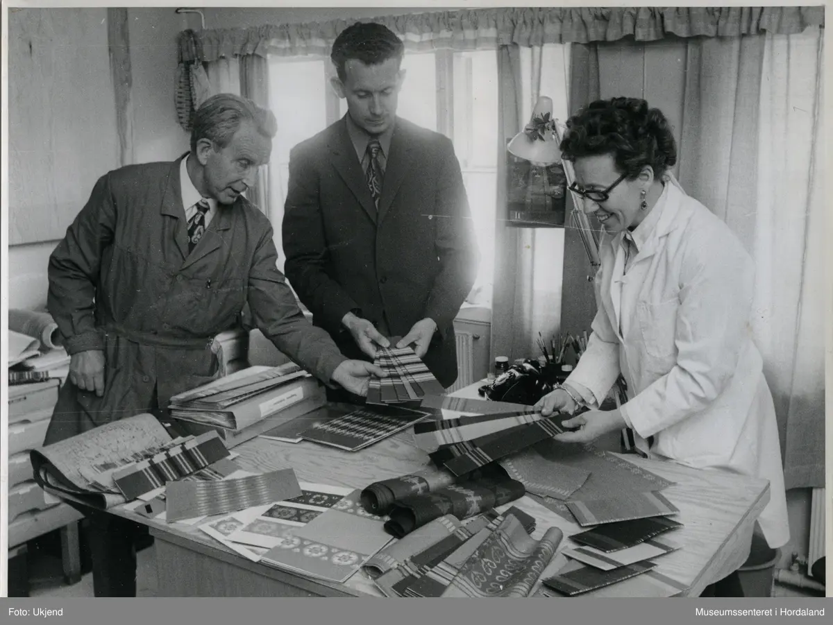 Kontormiljø på Trengereid Fabrikker, truleg ca. 1950-52. Tilsette studerer ulike typar varer.