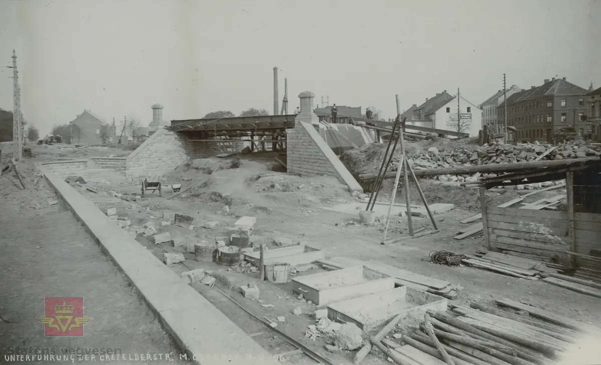 Album fra 1903-1908. Befaring under  bygging av  en  stålkonstruksjon for bæring  av jernbaneundergang. Forstøtningsmurer på begge sider.  Krefelder Strs. Mönchengladbach 18.10.1906.