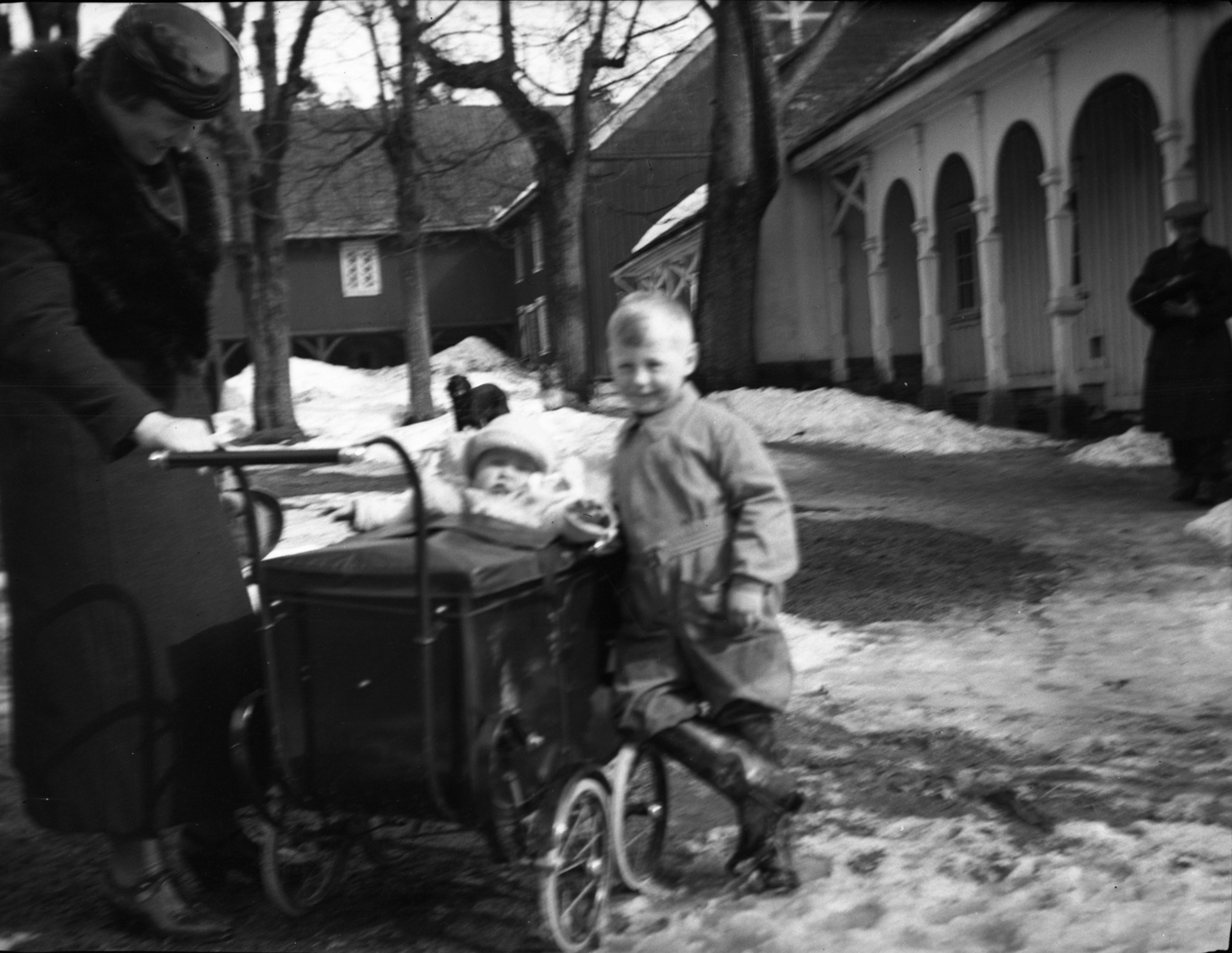 Fotoarkivet etter Gunnar Knudsen. En kvinne med to barn, til høyre i bildet står det en mann. Bildet er tatt på Borgestad gård og den stående gutten er ant. Diderik Cappelen F. 1932, Gunnar Knudsens eldste oldebarn.