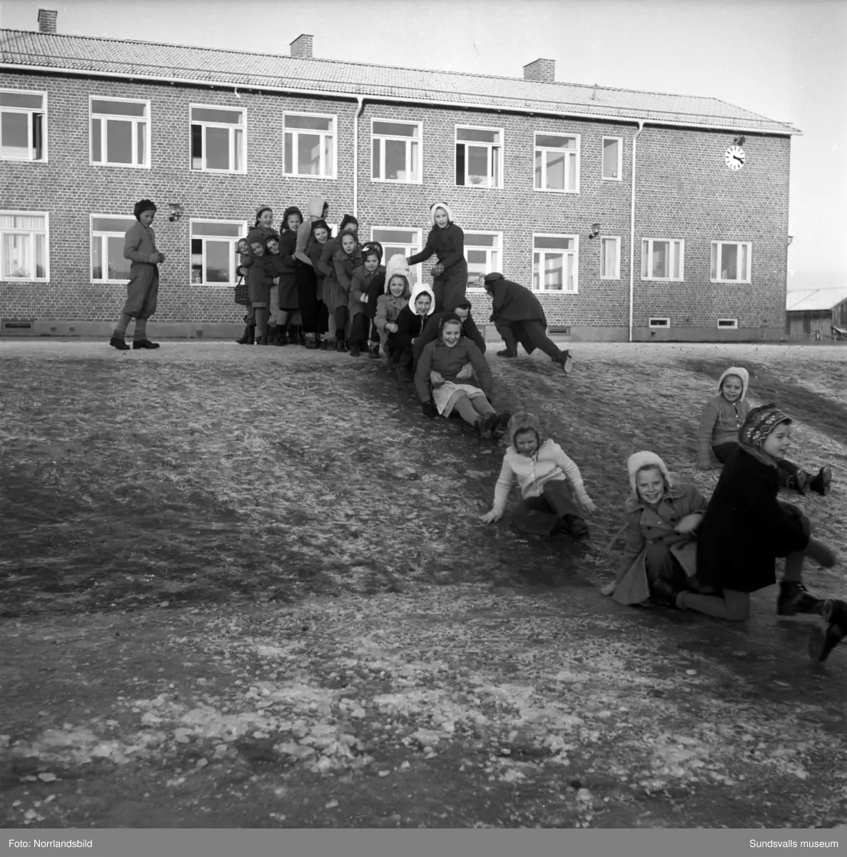 Reportagebilder från Stöde skola, tidigare Slättåbygdens skola. Exteriör, interiör, lektioner i klassrummen, rastlek, elever, personal, lärarrum och affischförråd. Bild 2: busschauffören är Jonas Malmgren. Bild 8: Harry Wiberg. Bild 9: Maritta Larsson. Bild 12: vaktmästare Adrian Almgren. Bild 14: Johan Näsström. Bild 15: Lärarrummet med: Längst bak från vänster Karin Jonsson, Linnea Sterner, Roland Källsäter och Johan Näsström. Längst fram sitter Märta Näsström och Hildegard Svensson.