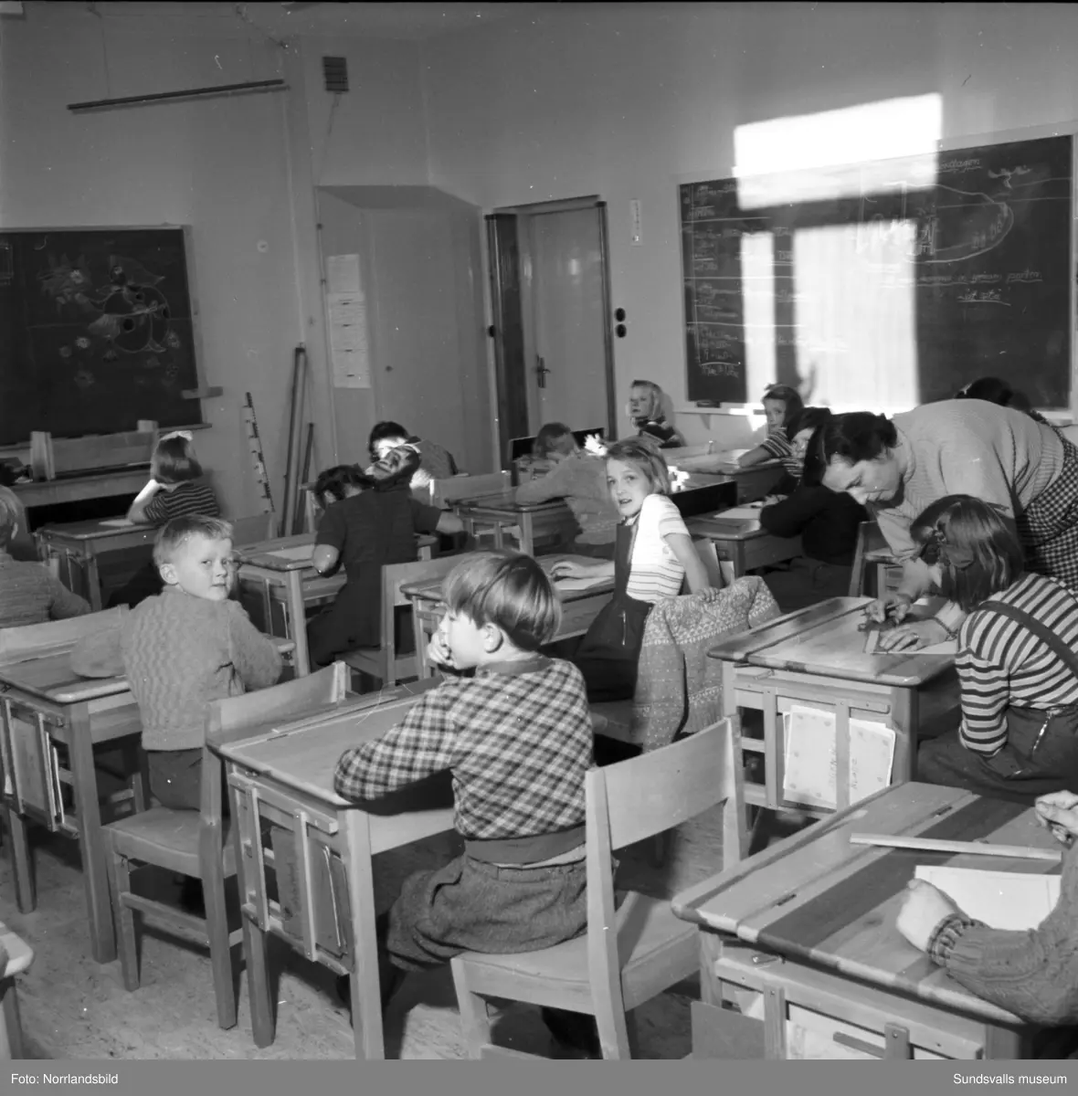 Reportagebilder från Stöde skola, tidigare Slättåbygdens skola. Exteriör, interiör, lektioner i klassrummen, rastlek, elever, personal, lärarrum och affischförråd. Bild 2: busschauffören är Jonas Malmgren. Bild 8: Harry Wiberg. Bild 9: Maritta Larsson. Bild 12: vaktmästare Adrian Almgren. Bild 14: Johan Näsström. Bild 15: Lärarrummet med: Längst bak från vänster Karin Jonsson, Linnea Sterner, Roland Källsäter och Johan Näsström. Längst fram sitter Märta Näsström och Hildegard Svensson.
