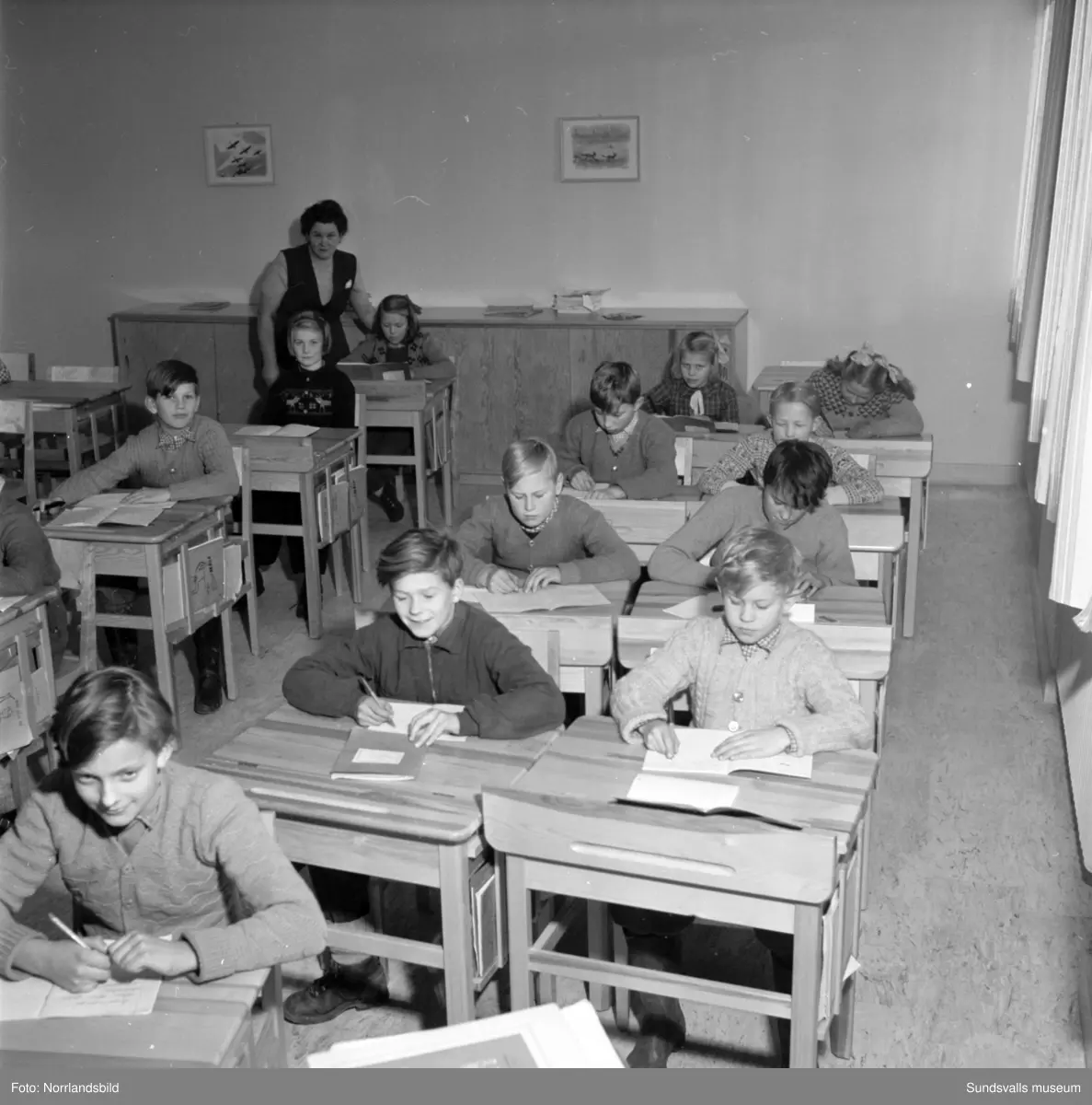 Reportagebilder från Stöde skola, tidigare Slättåbygdens skola. Exteriör, interiör, lektioner i klassrummen, rastlek, elever, personal, lärarrum och affischförråd. Bild 2: busschauffören är Jonas Malmgren. Bild 8: Harry Wiberg. Bild 9: Maritta Larsson. Bild 12: vaktmästare Adrian Almgren. Bild 14: Johan Näsström. Bild 15: Lärarrummet med: Längst bak från vänster Karin Jonsson, Linnea Sterner, Roland Källsäter och Johan Näsström. Längst fram sitter Märta Näsström och Hildegard Svensson.