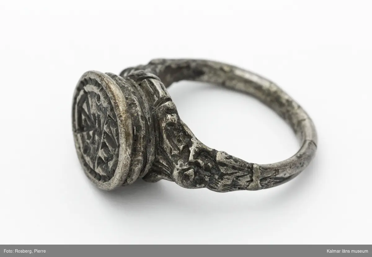 KLM 16729. Sigillring, av silver. Trind ring, oval tjock klack. Renässansornament i övergången mellan ring och klack. I klacken bokstäverna MN samt vapensköld med bomärke. Datering: 1500-tal eller tidigt 1600-tal.