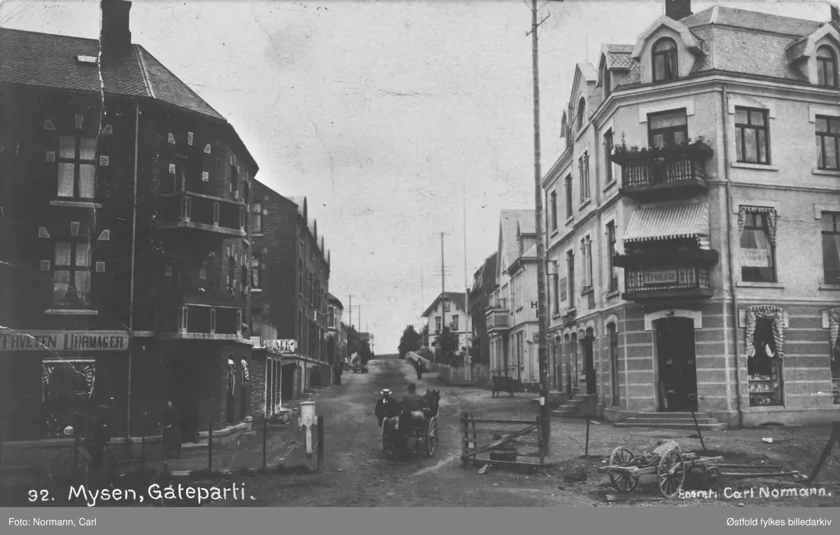 Gateparti fra Storgata i Mysen, Eidsberg ca. 1910-15. Ved jernbanestasjonen. 

Skilt for Thveten Uhrmager og Cafe Central. Skilt for Tandlæge.