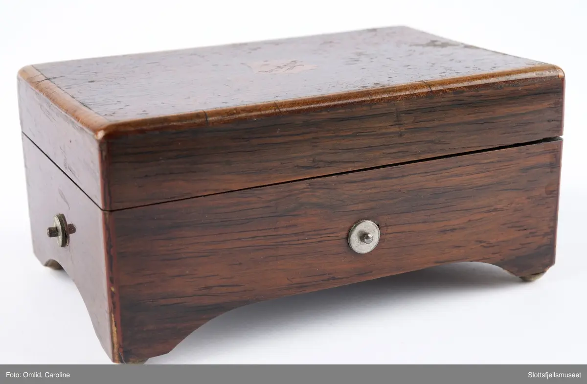 Polert rektangulær eske som inneholder anlegget til spilledåsen.