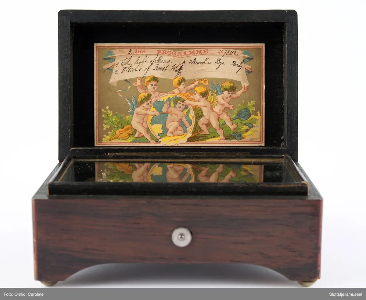 Polert rektangulær eske som inneholder anlegget til spilledåsen.