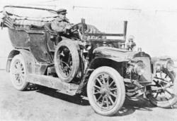 Mann sitter og kjører bil, bilde av Karl E. Mølmen som var s